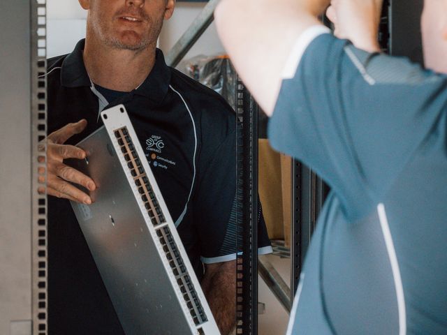 Two team members fitting a patch panel into a data rack