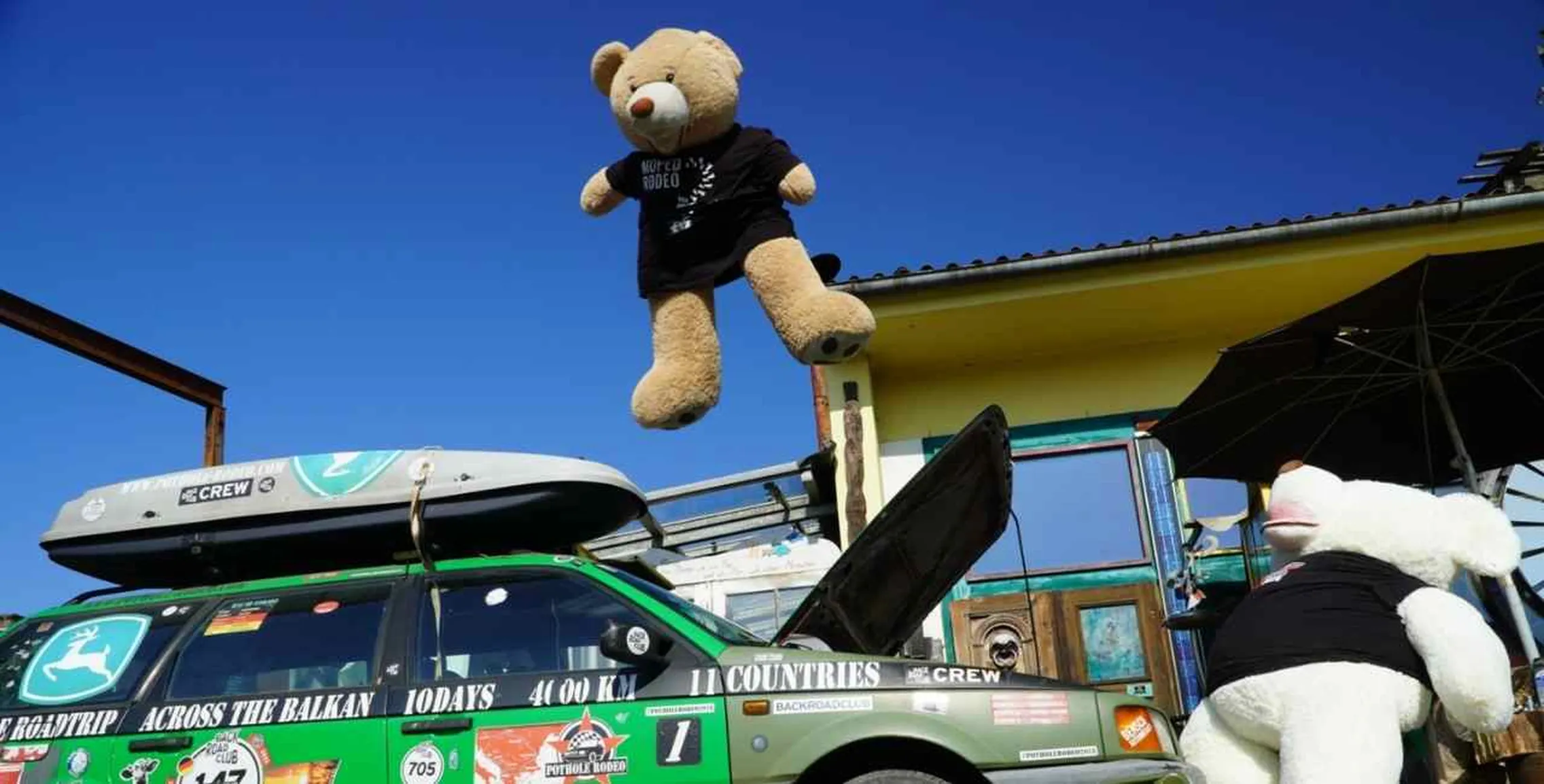 Das BackRoadClub-Maskottchen Lenny fliegt über ein Rallye-Fahrzeug des Pothole Rodeo.