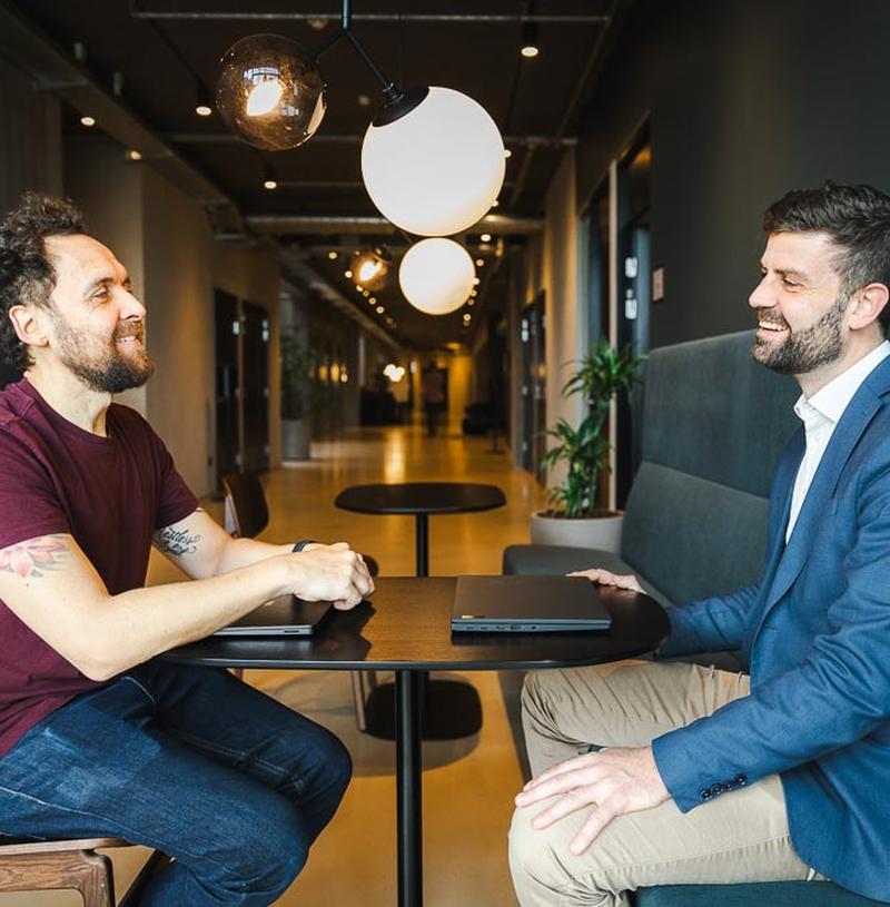 Jacob taler med samarbejdspartner i mødelounge om AI Act konsulent hjælp og compliance