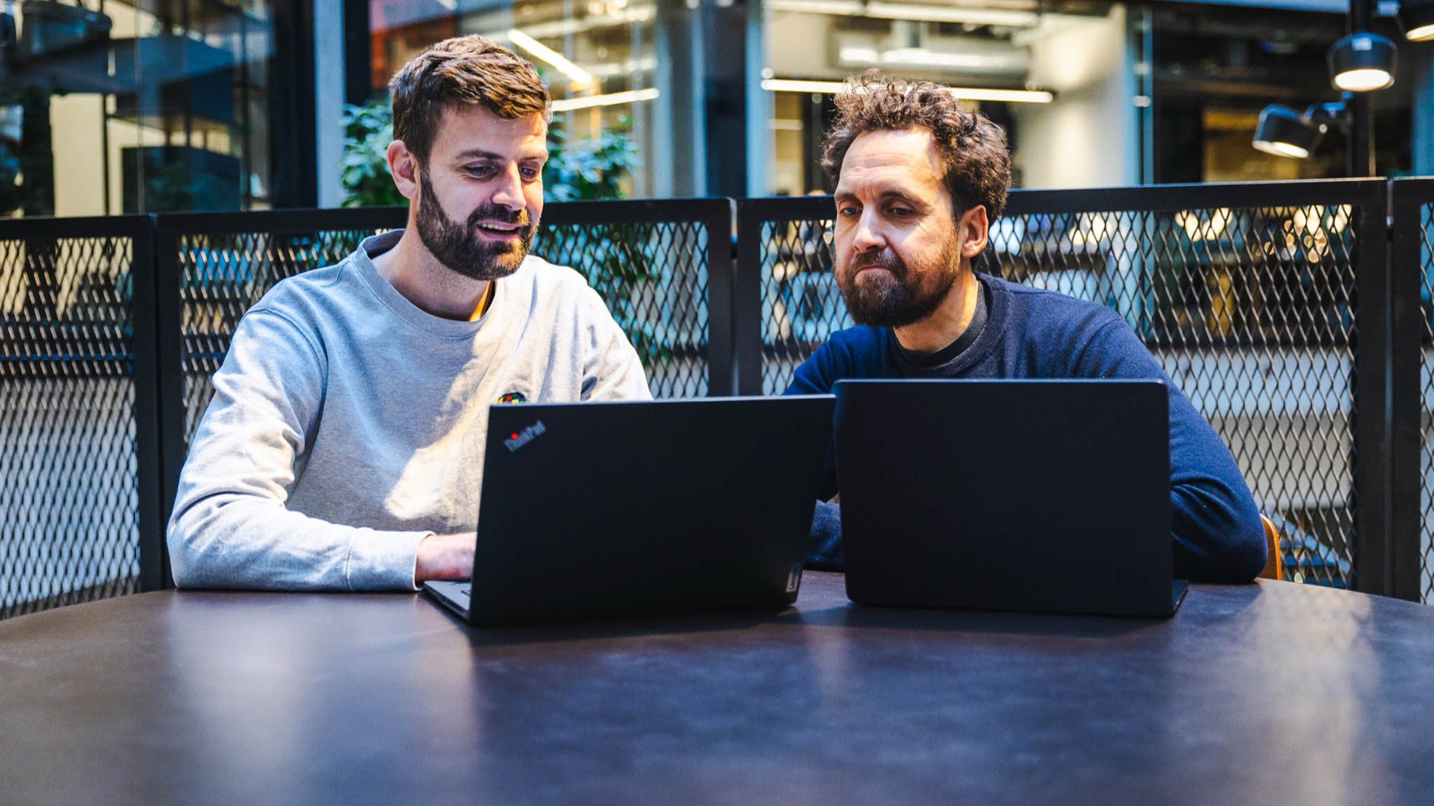 Jacob og Frederick vurderer AI automation ved laptops i et mødelokale uden skærmtekst eller diagrammer.