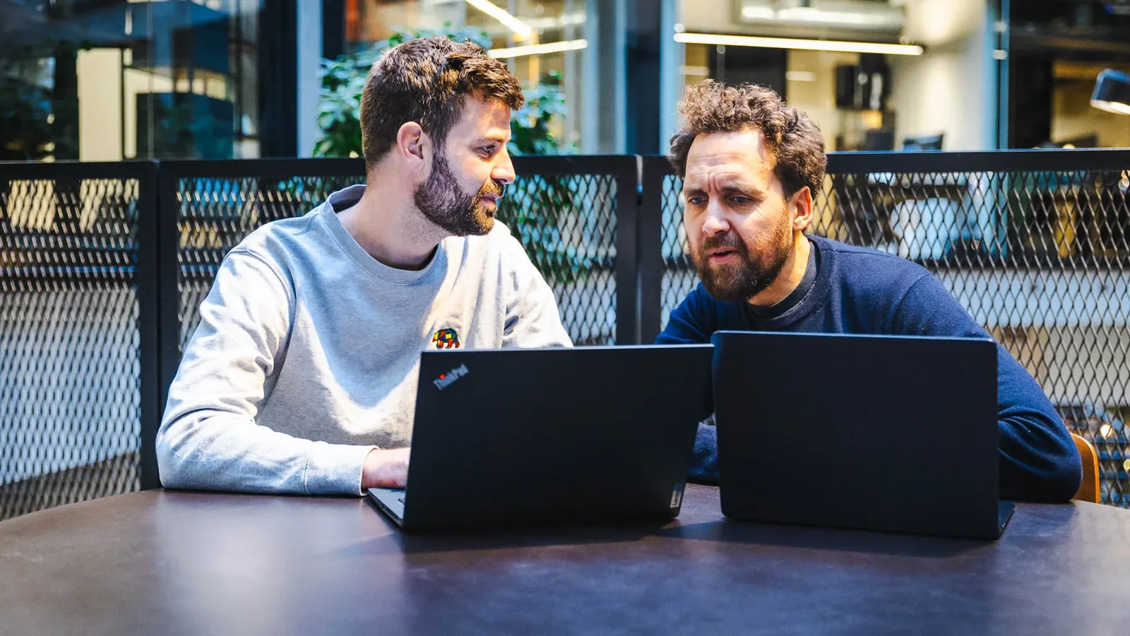 Jacob og Frederick vurderer AI tools ved laptops i et HverdagsAI-møde om budget og værdi.