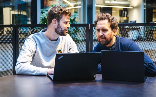 Jacob og Frederick vurderer AI tools ved laptops i et HverdagsAI-møde om budget og værdi.