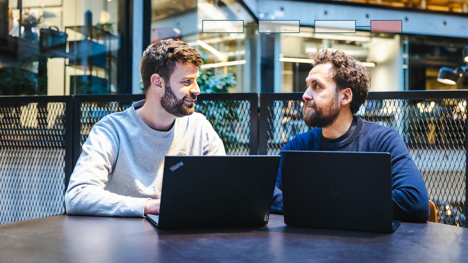 Jacob og Frederick vurderer værktøjsvalg på laptops med workflowkort for AI automation.