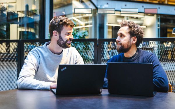 Jacob og Frederick vurderer værktøjsvalg på laptops med workflowkort for AI automation.