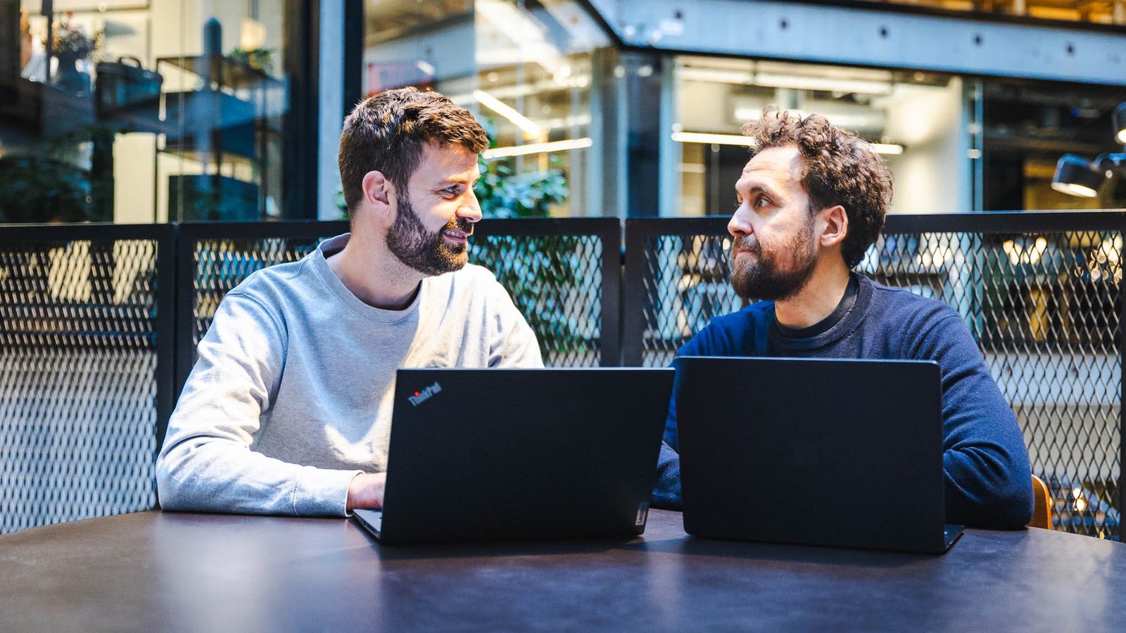 To undervisere vurderer værktøjsvalg på laptops i et mødelokale til AI automation.
