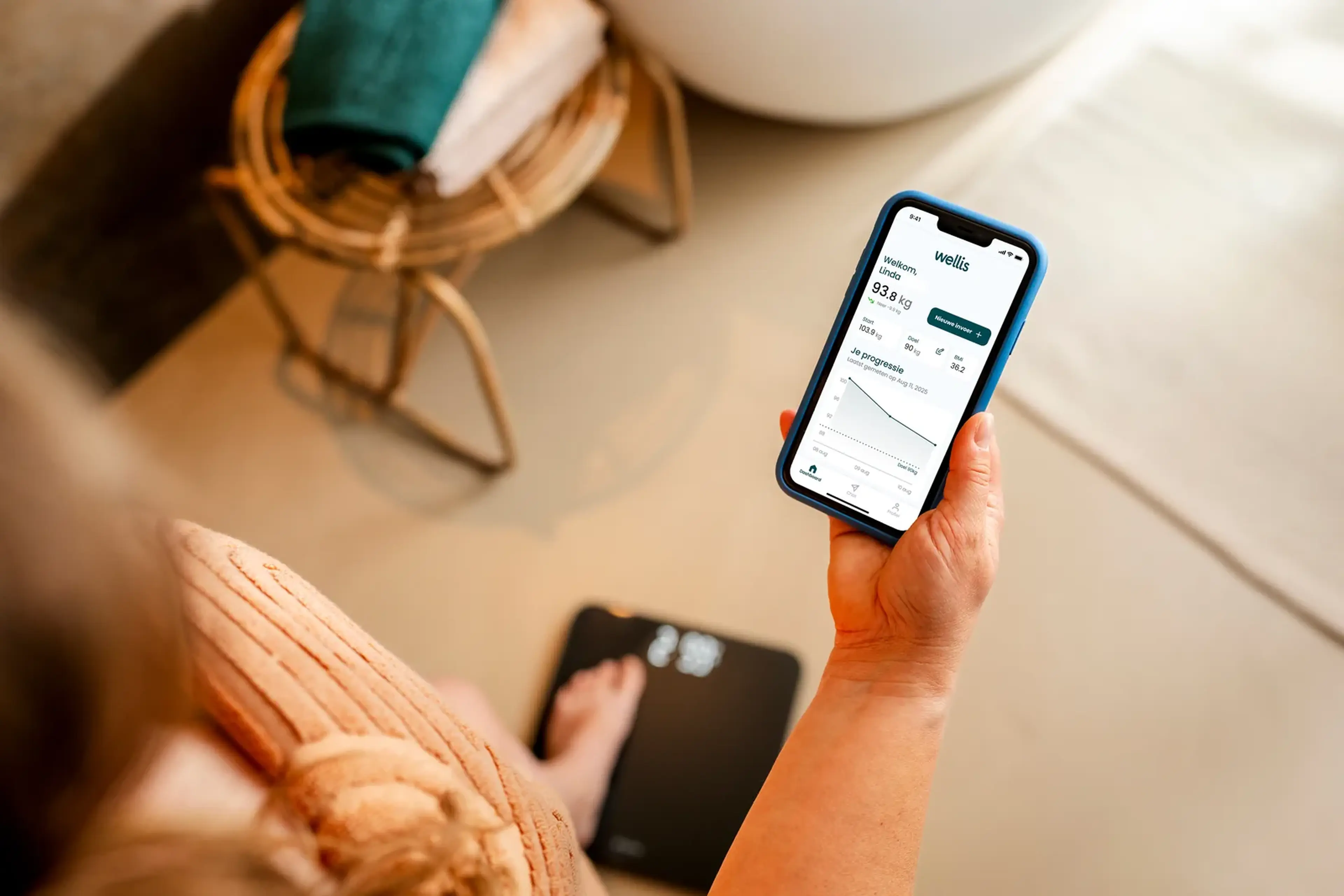 Vrouw staat op een weegschaal en bekijkt haar gewichtsverloop in de Wellis-app