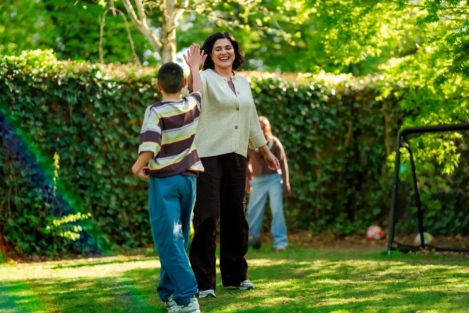Vrouw geeft in de tuin een high five aan een jongen