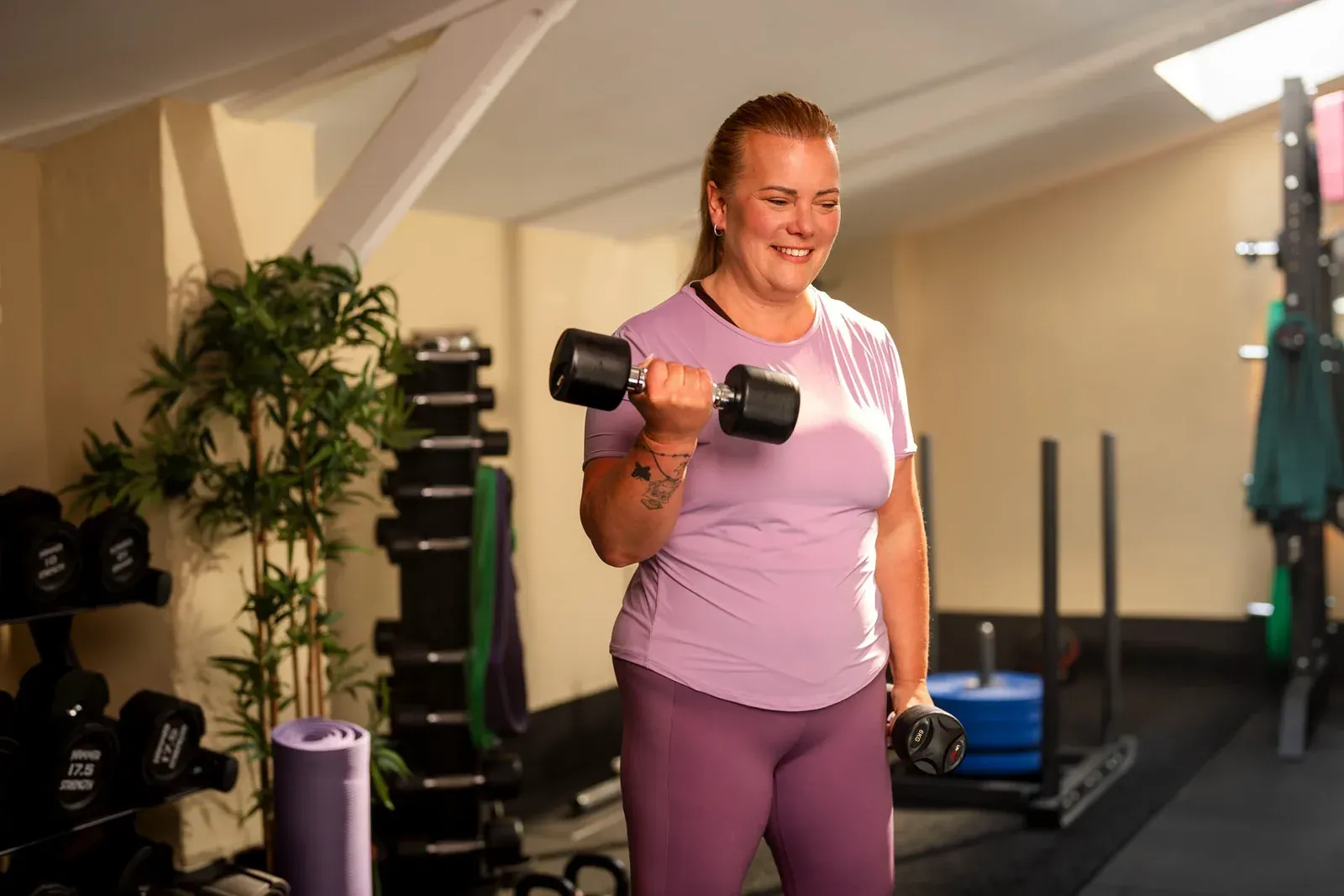 Vrouw traint met een dumbbell in een fitnessruimte