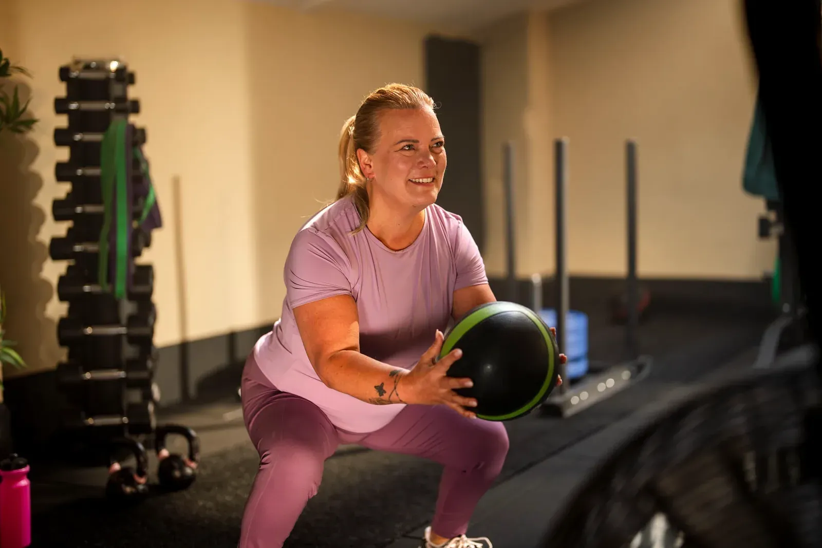 Vrouw doet een squat met een medicijnbal in een fitnessruimte