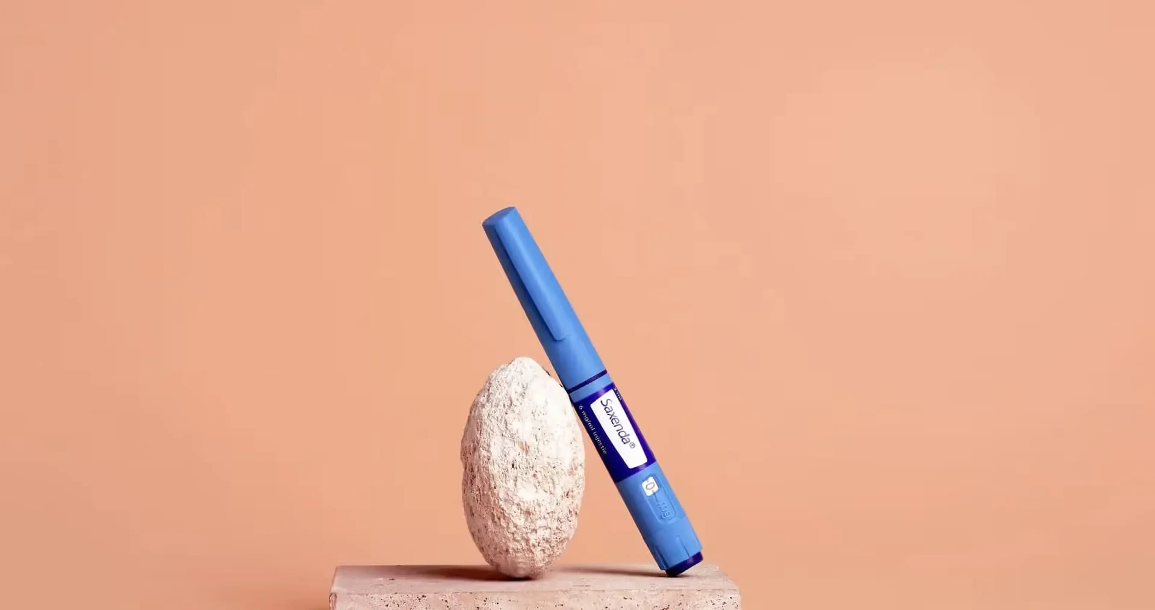 Blauwe Saxenda-injectiepen leunt tegen een lichte steen op een stenen sokkel