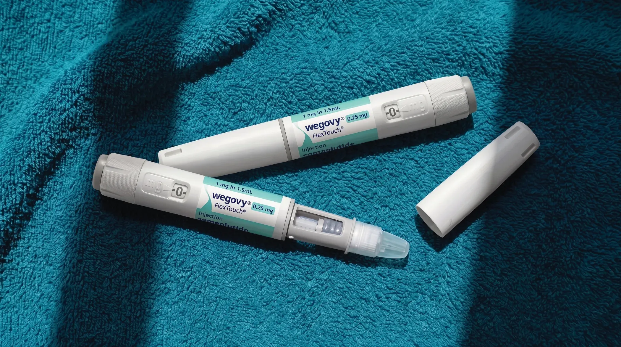Twee Wegovy-injectiepennen op een blauwgroene handdoek