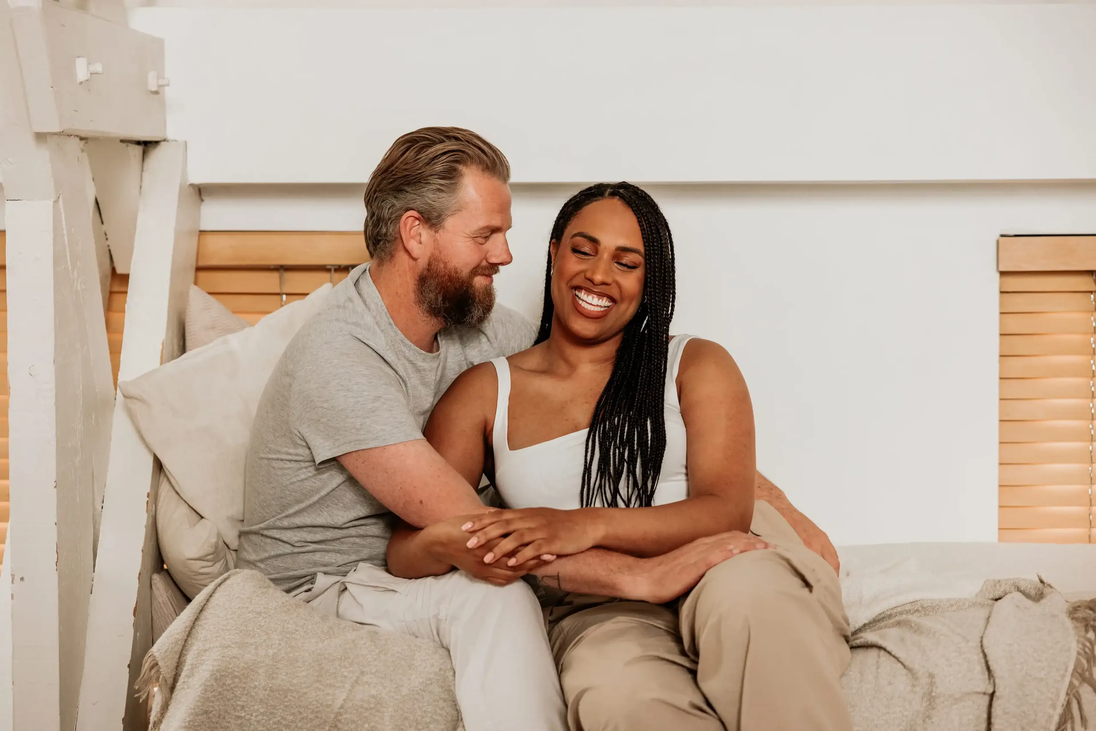 Man en vrouw zitten lachend samen op bed – zo bereid je je injectie voor