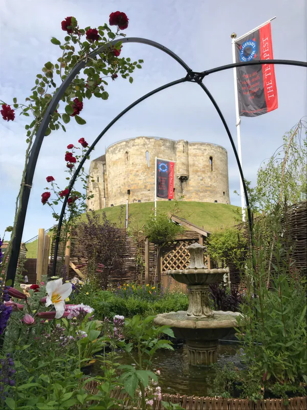 A traditional garden beside a period stone building, with a sundial