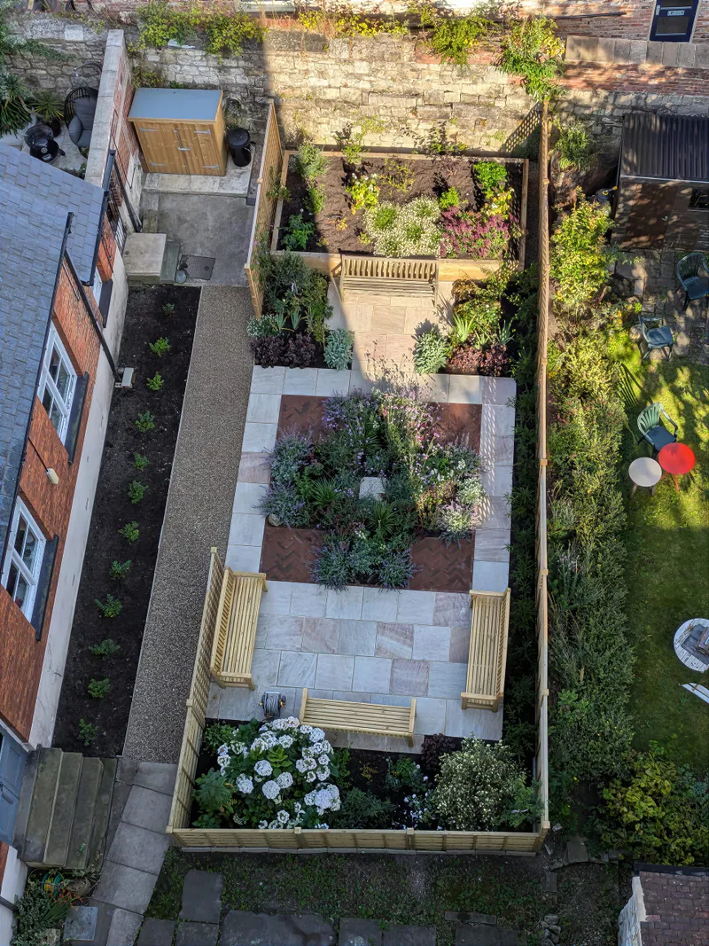 A walled town garden with an archway and climbing plants