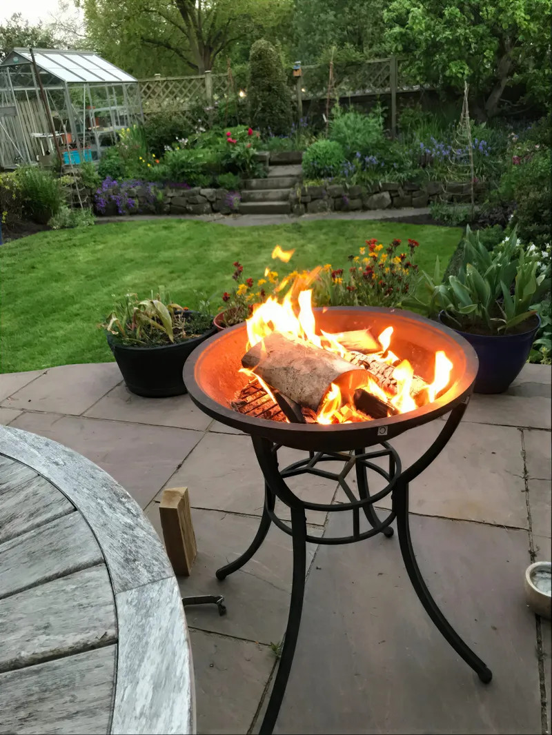 A lit fire pit on a garden patio in the evening