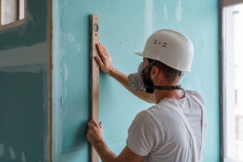 Handwerker setzt eine Wasserwaage an eine Trockenbauwand