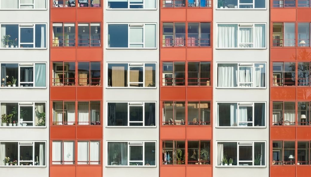Wohnblock in Rot und Weiss mit gleichmaessigem Fensterraster