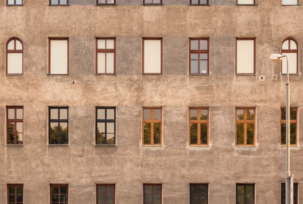 Altbaufassade mit farbigen Fensterrahmen in gleichmaessigen Reihen