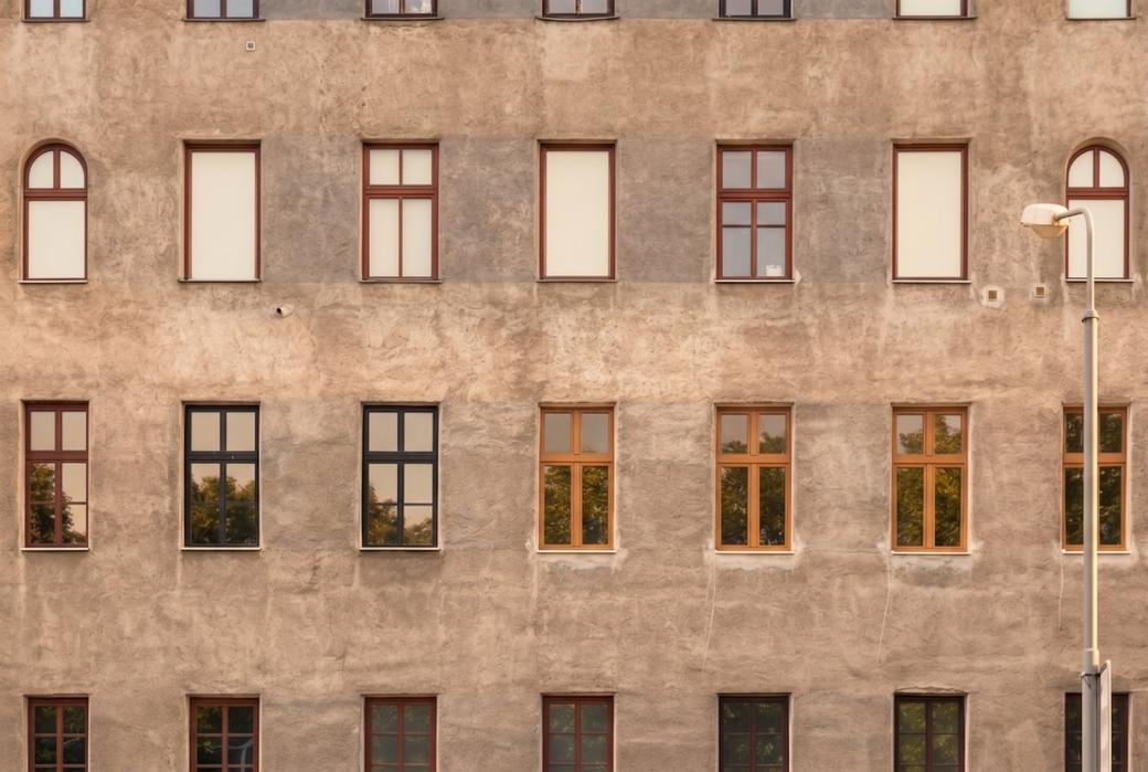 Altbaufassade mit farbigen Fensterrahmen in gleichmaessigen Reihen