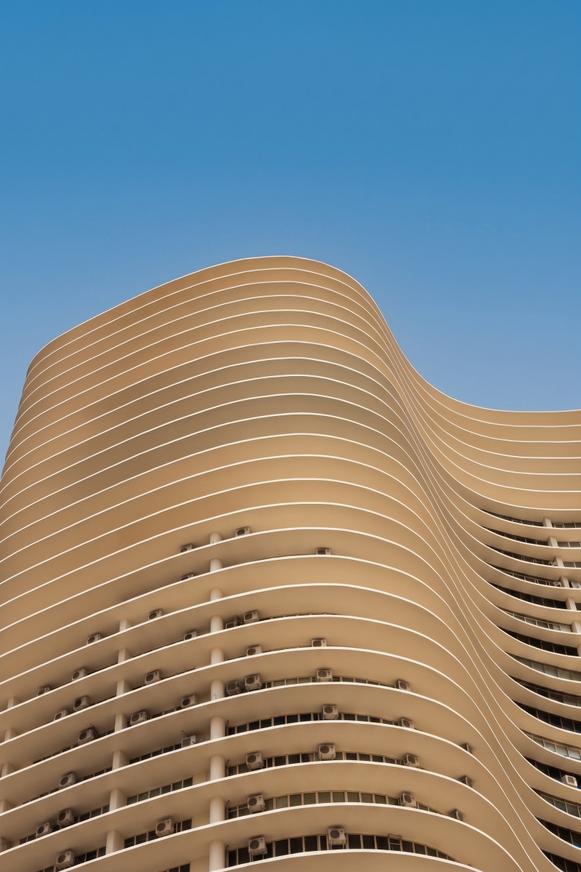 Wellenfoermige Hochhausfassade in der Untersicht gegen den Himmel
