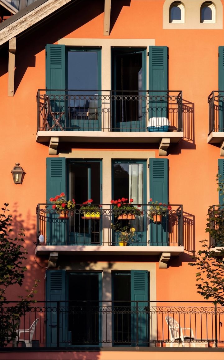 Orange Fassade mit tuerkisen Fensterlaeden und Balkonen