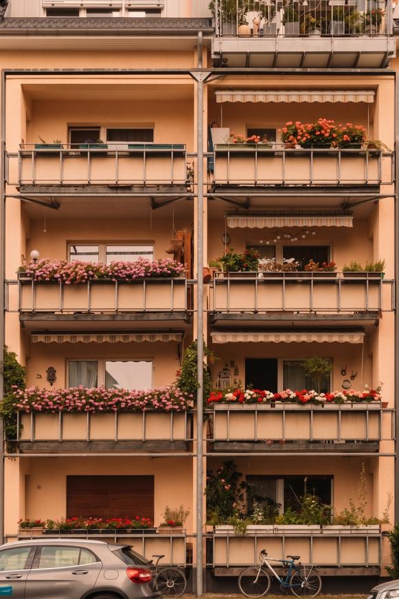 Facciata di un condominio con balconi fioriti e fioriere nella luce calda