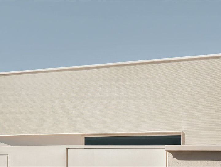 Cremefarbene Wellenfassade mit umlaufendem Fensterband