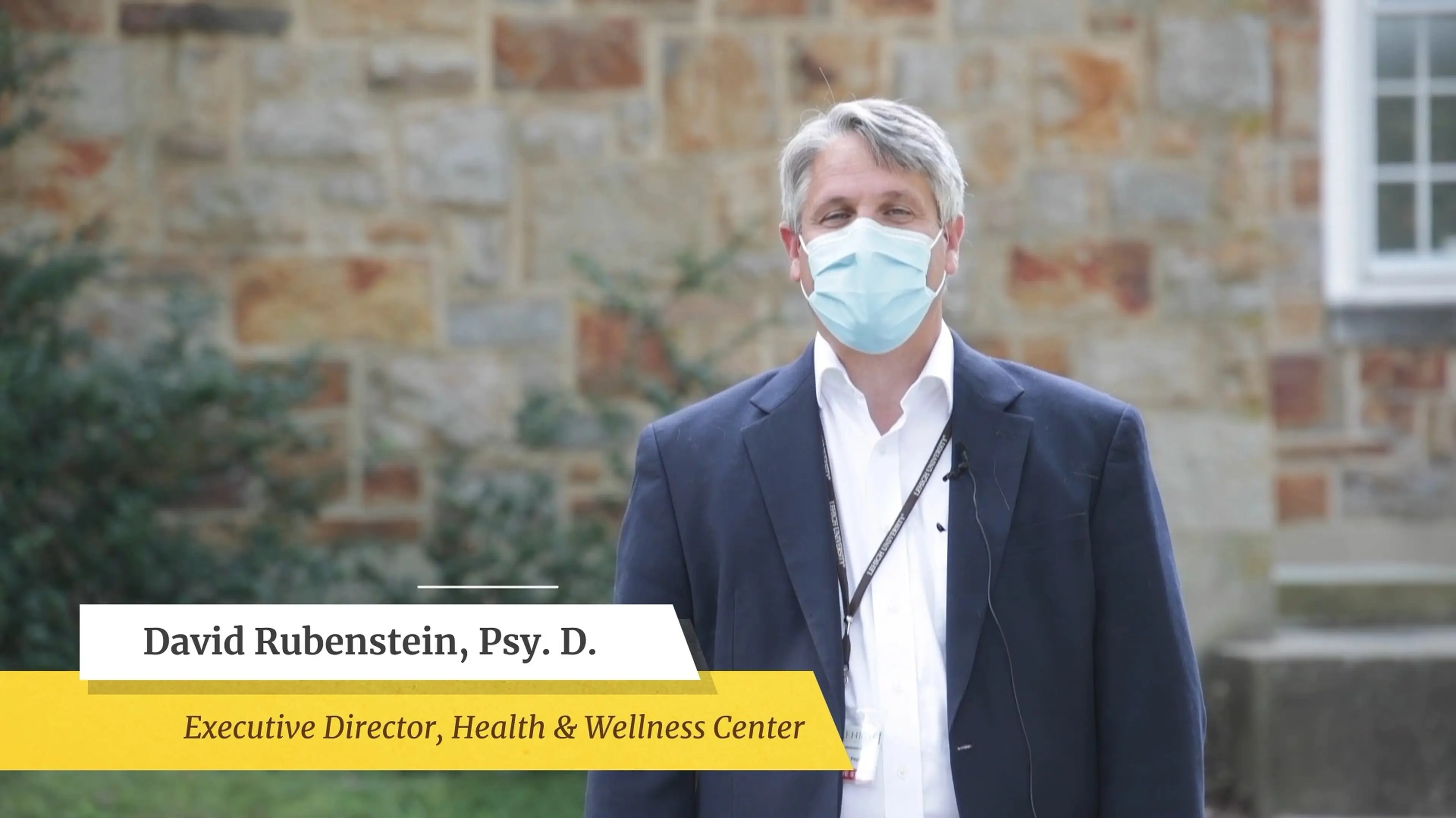 Live-action health center director speaking to camera outside a campus building, with a name and title lower third, from a Motifmotion healthcare video