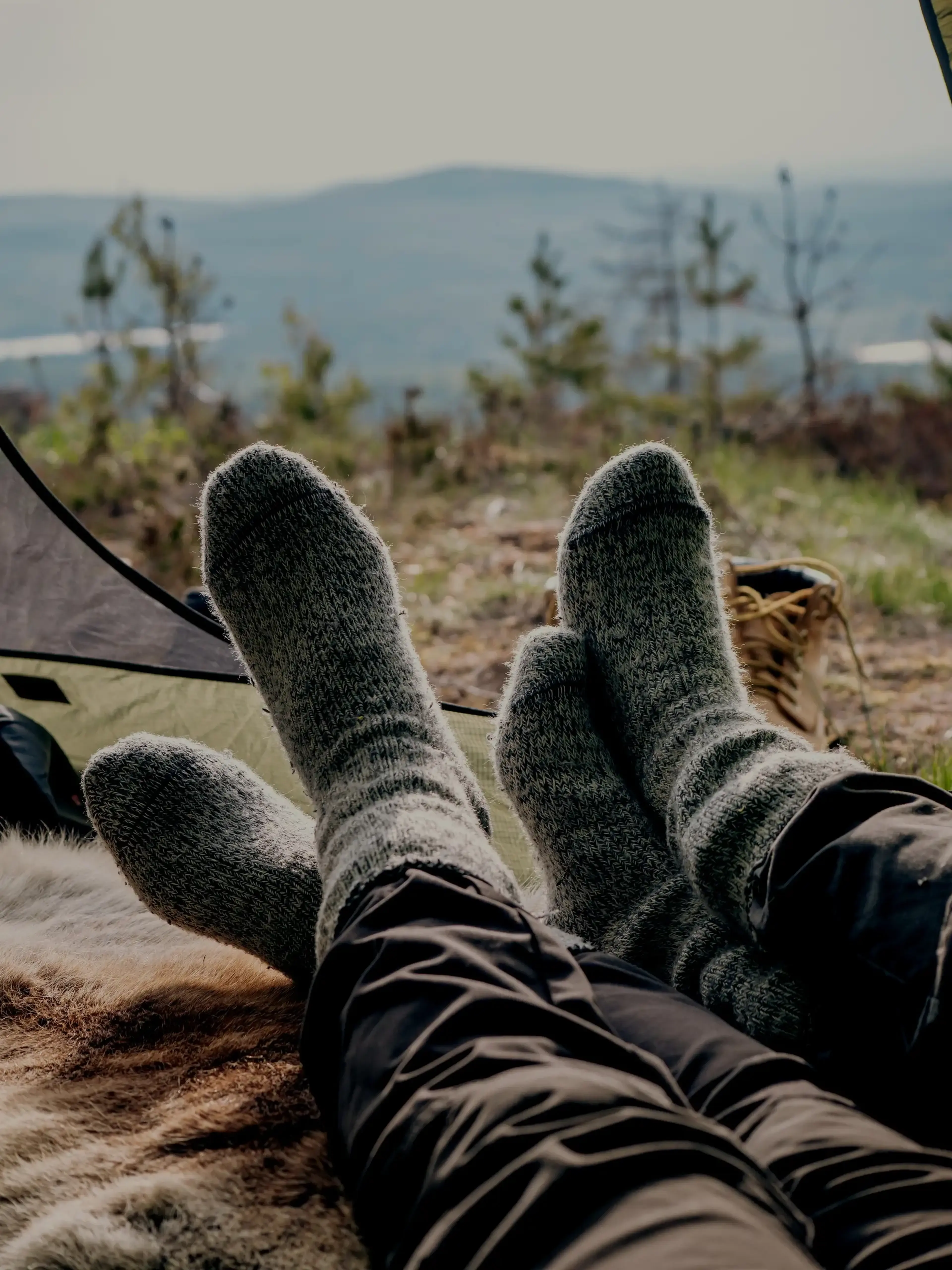Two people wearing warm socks as they take in the breathtaking mountain views beyond.