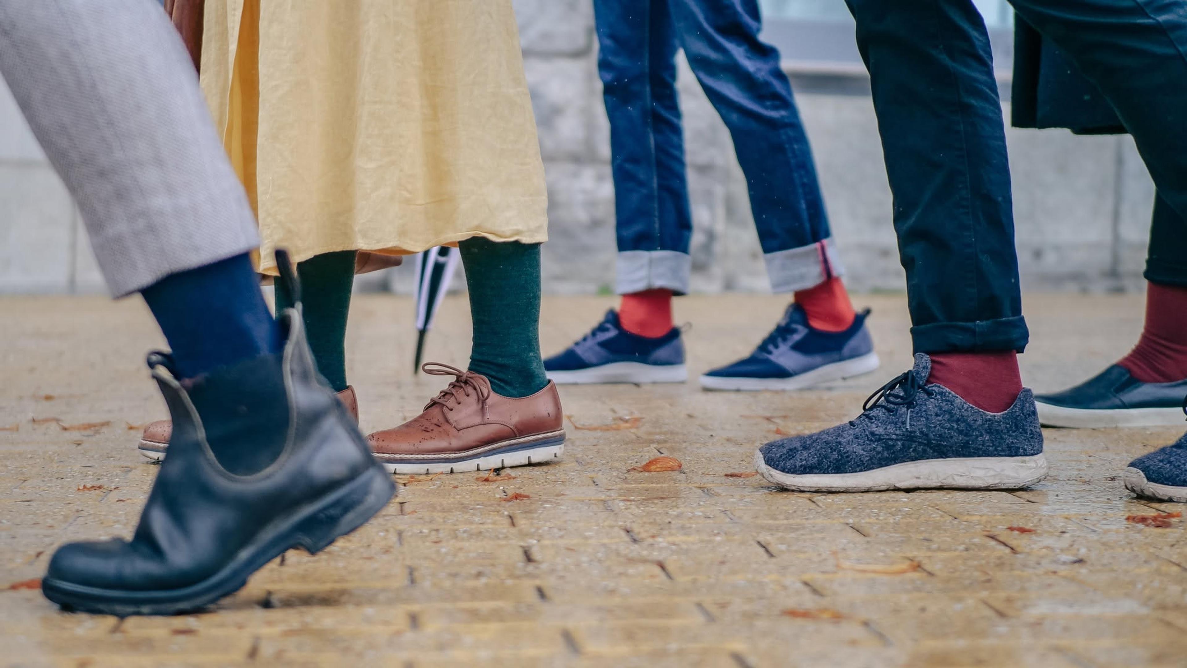 A lively group of friends displaying their stylish shoes and socks, sharing laughter and good times together.
