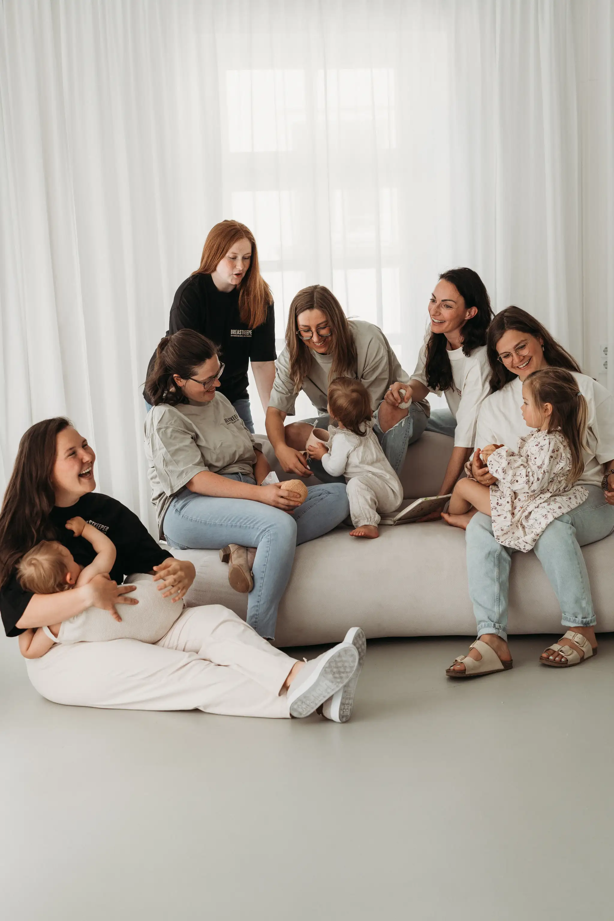 Gruppe von Breastkeeperinnen mit Kindern auf einem Sofa – warme Community-Atmosphäre im Breastkeeper Institut