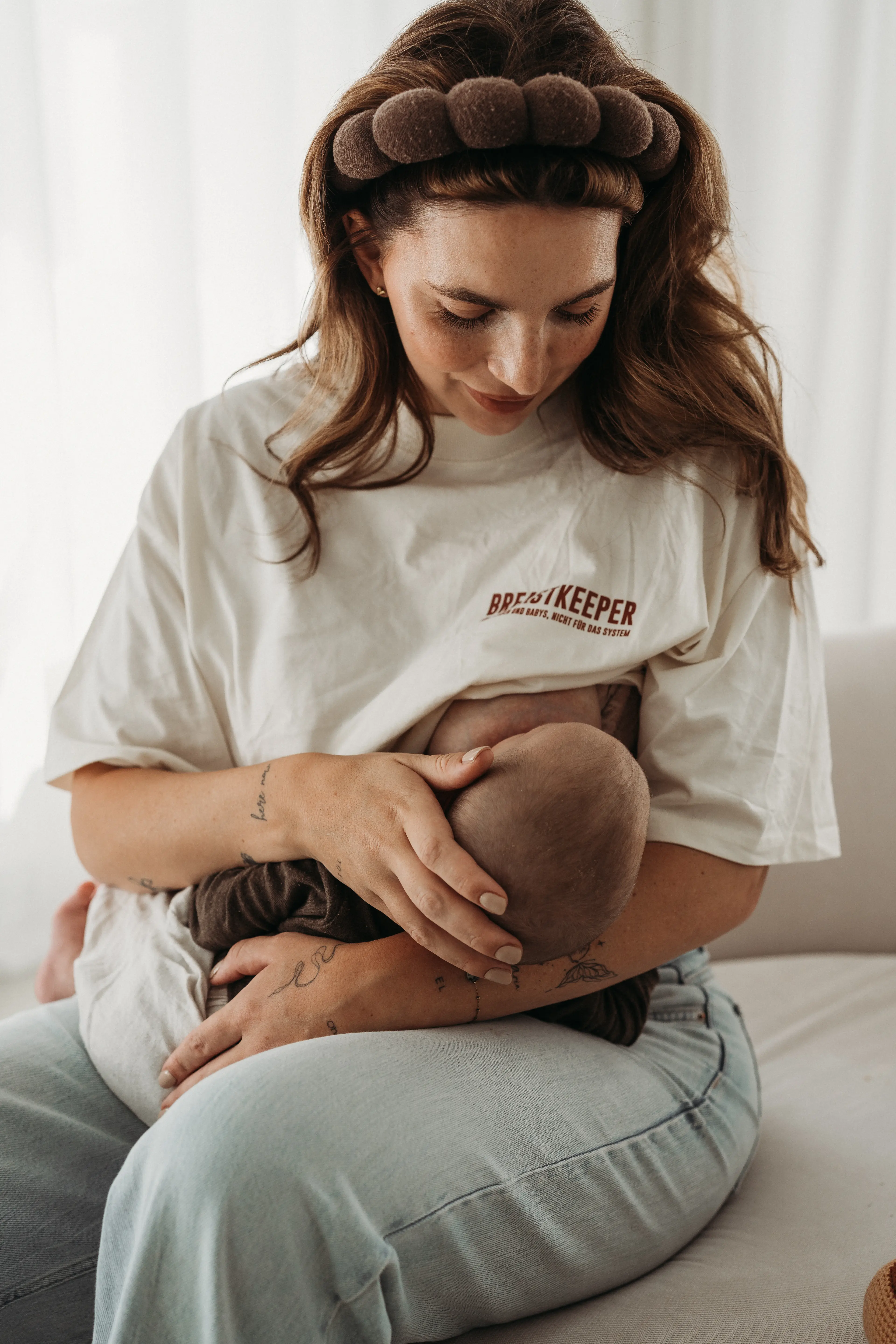 Junge Mutter im Breastkeeper T-Shirt hält ihr Baby liebevoll im Arm