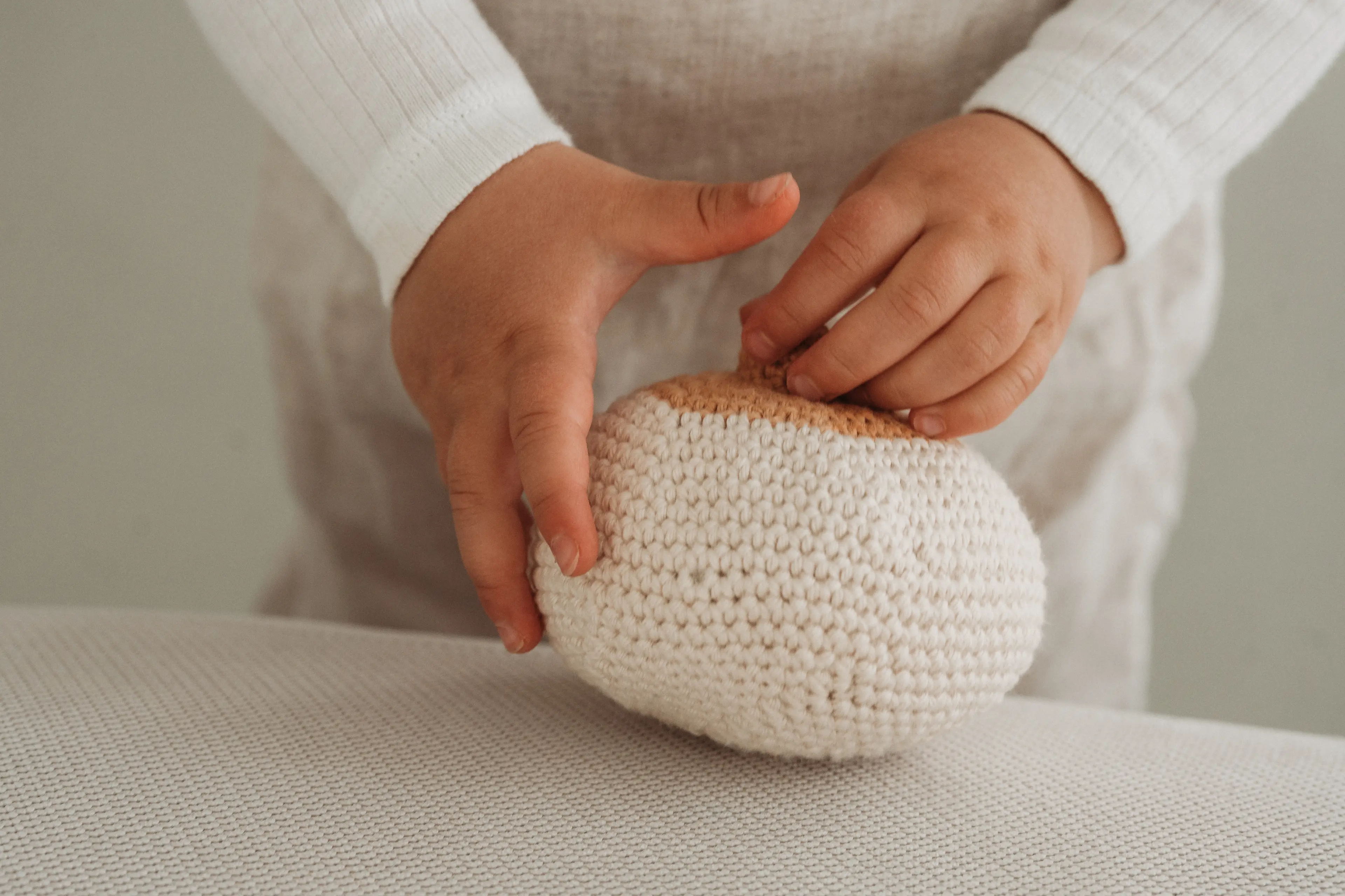 Kleine Kinderhand berührt ein gehäkeltes Brust-Modell – taktiles Lehrmittel der Breastkeeper Ausbildung