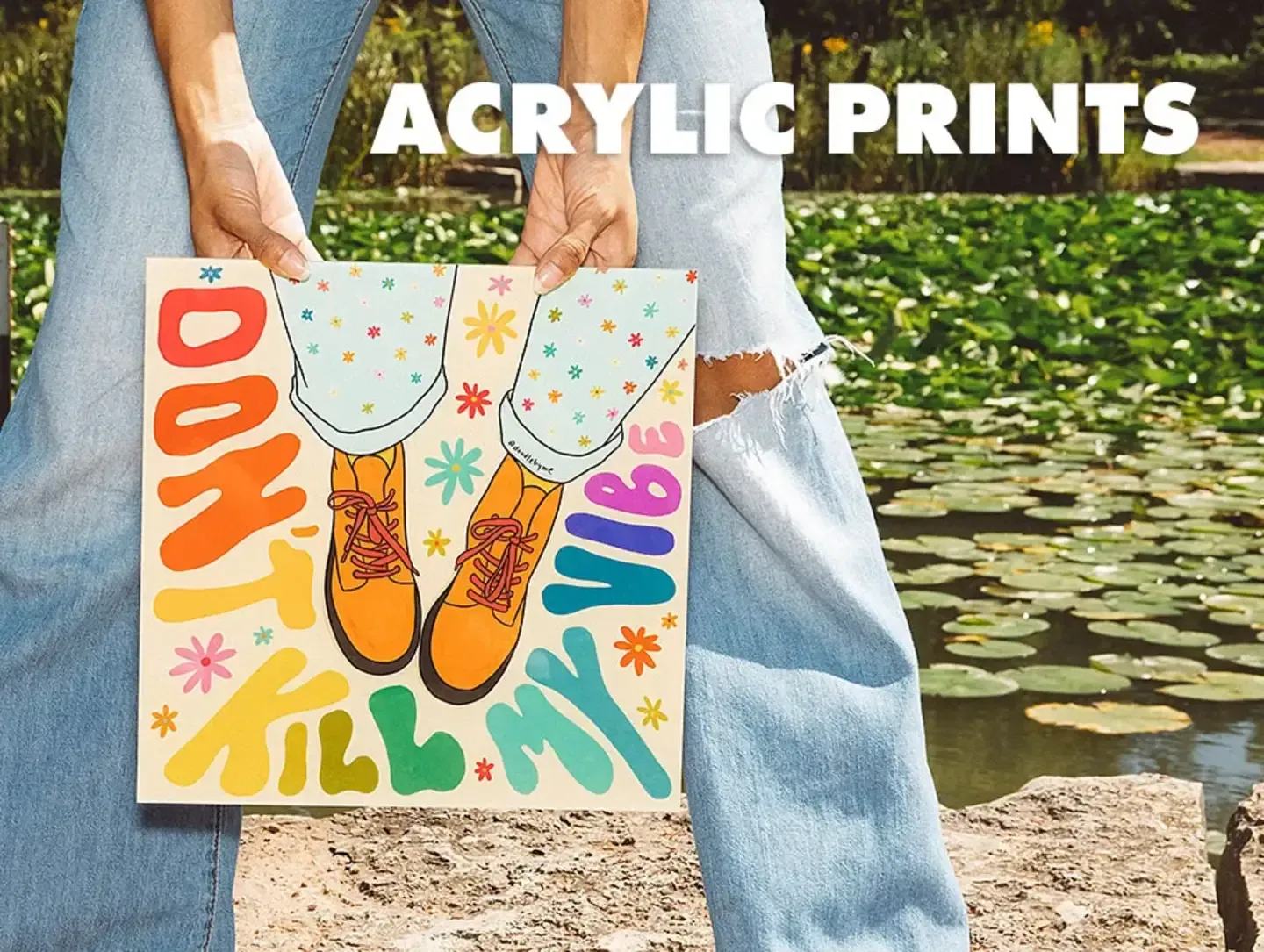 Person holding 'Don't Kill My Vibe' acrylic print outdoors near pond labelled 'Acrylic Prints'.