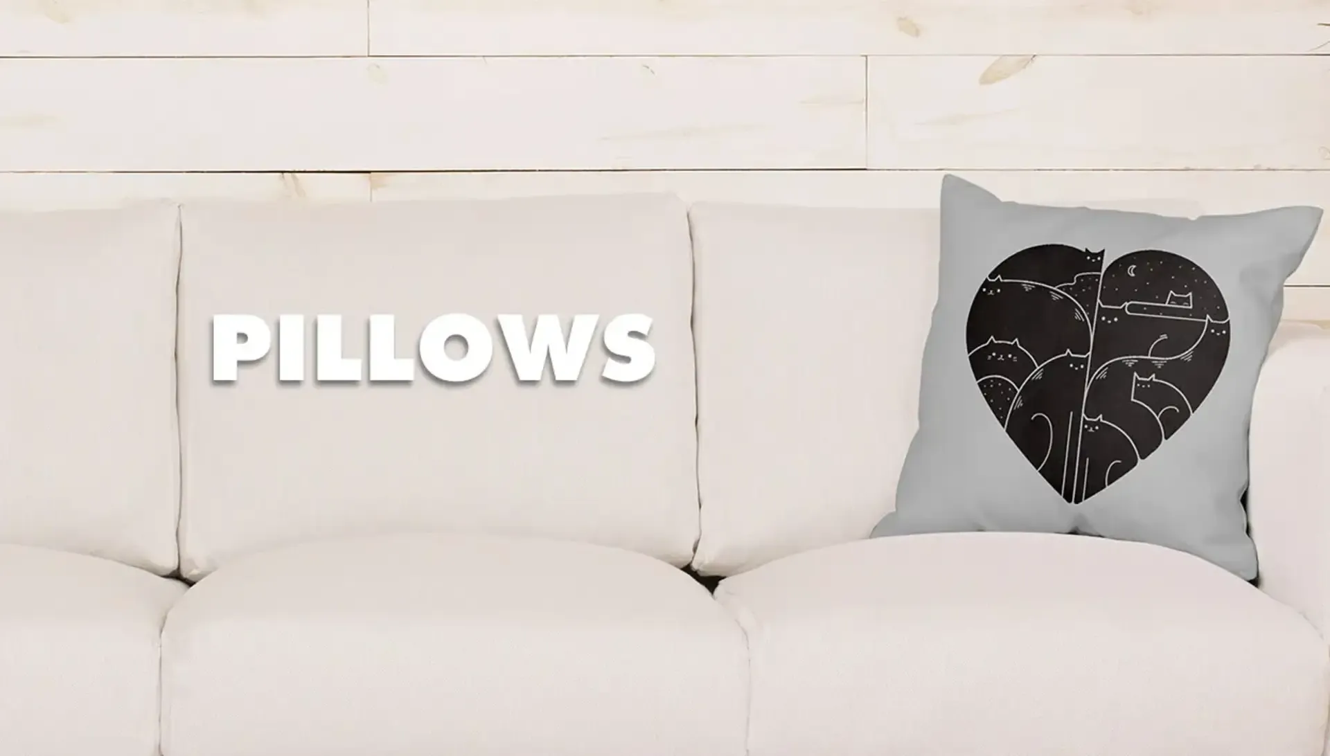 White sofa with cat heart graphic throw pillow in minimalist room with 'Pillows' text.