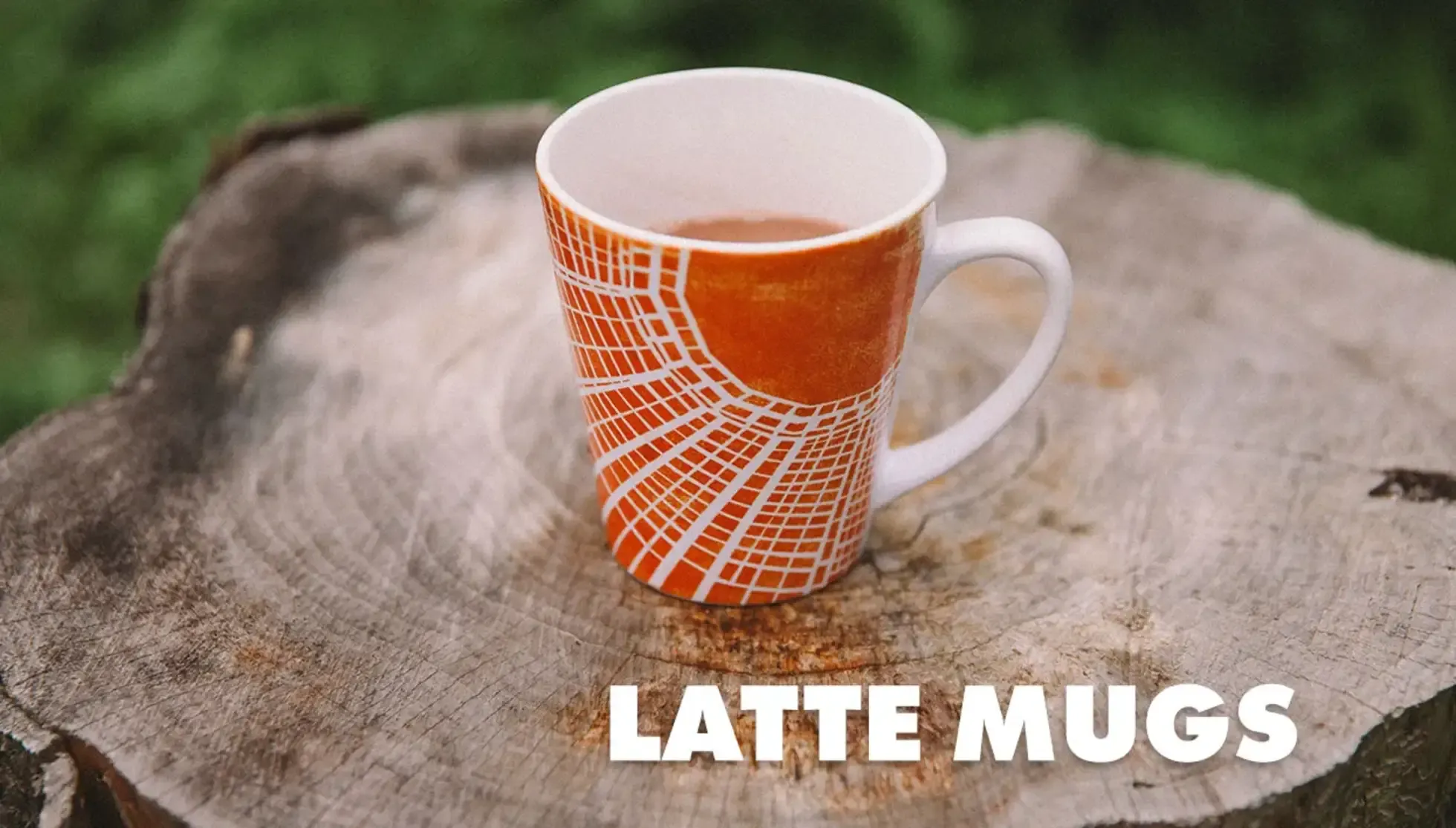 Orange and white geometric pattern latte mug on wood tree stump outdoors with 'Latte Mugs' text.