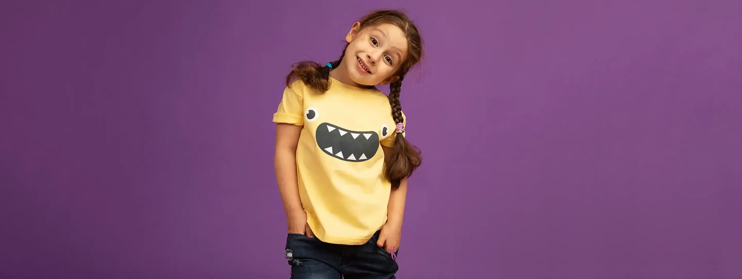 Young girl smiling in a yellow monster face t-shirt from Threadless