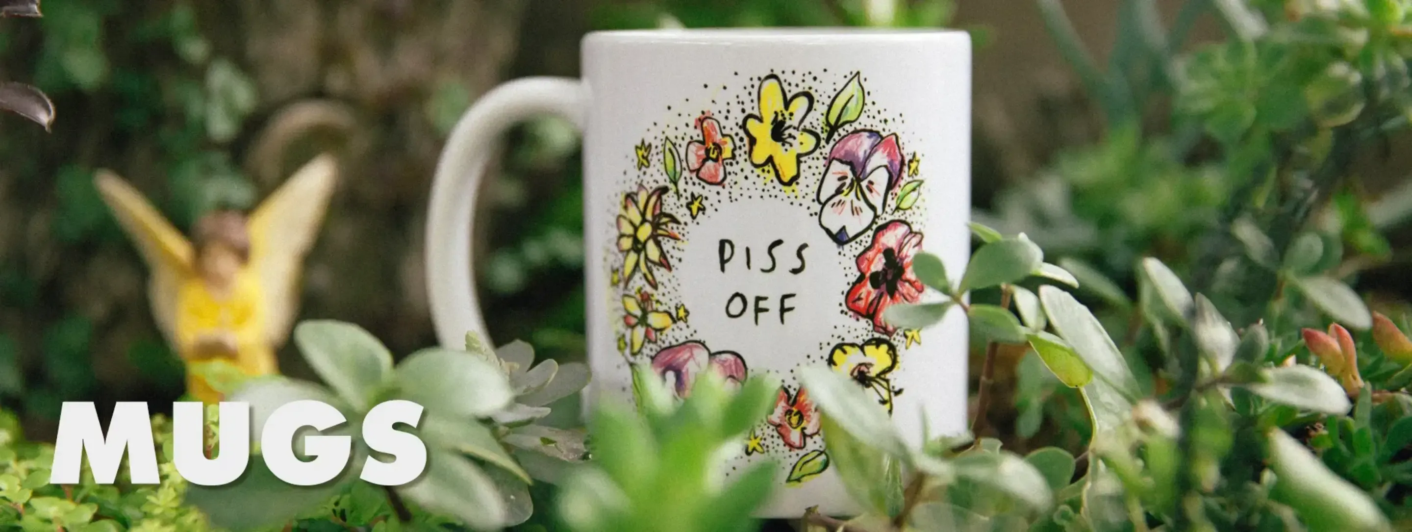 White ceramic mug with painted flowers and 'Piss Off' text on stone surface with greenery and 'Mugs' text overlay.