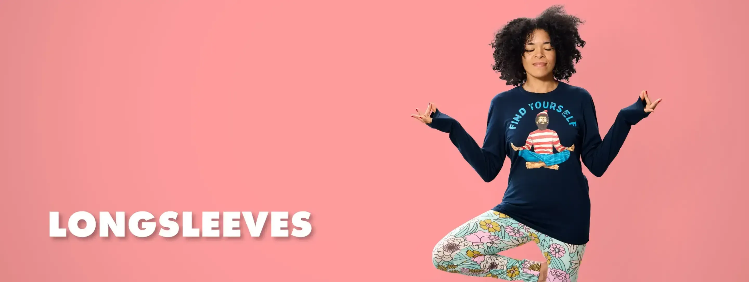 Woman in yoga pose wearing navy women's long sleeve t-shirt with Find Yourself Waldo graphic on pink backdrop.