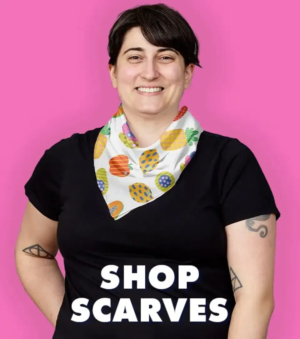 Smiling person wearing yellow patterned bandana scarf with pink wall backdrop showing 'Shop Scarves' text.