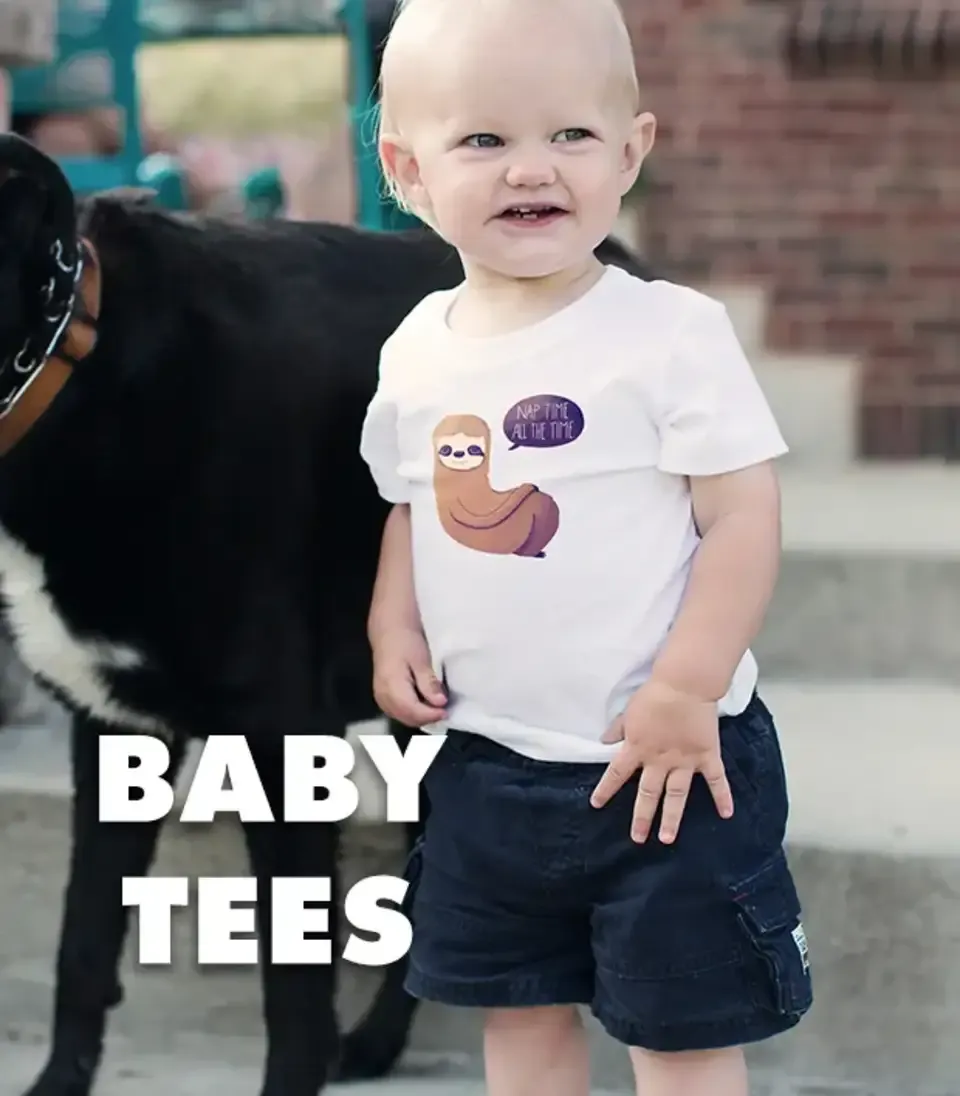 Baby in white t-shirt with happy worm graphic standing near black dog labelled 'Baby Tees'.