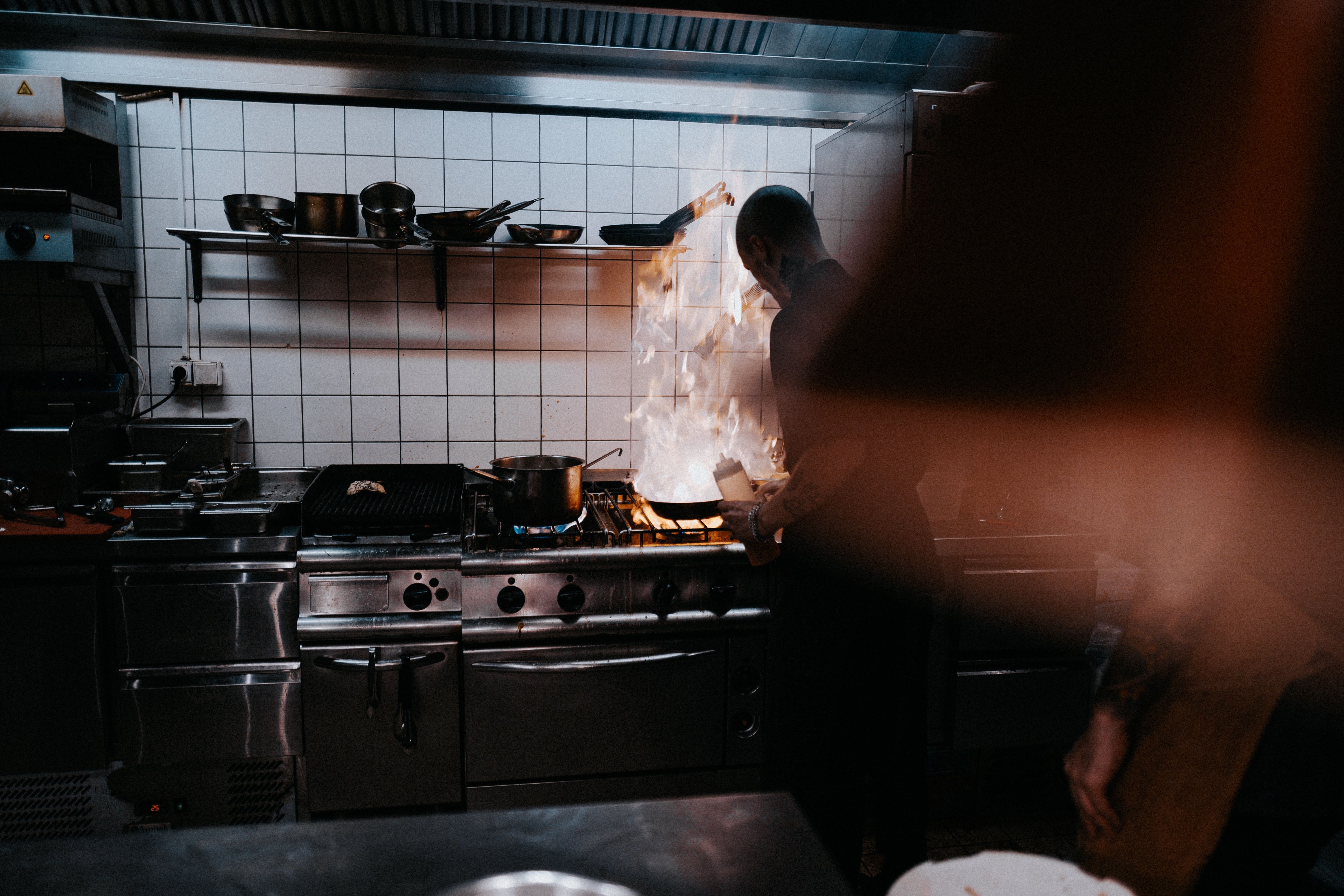 cuoco in cucina prepara un piatto con tecnica flambé