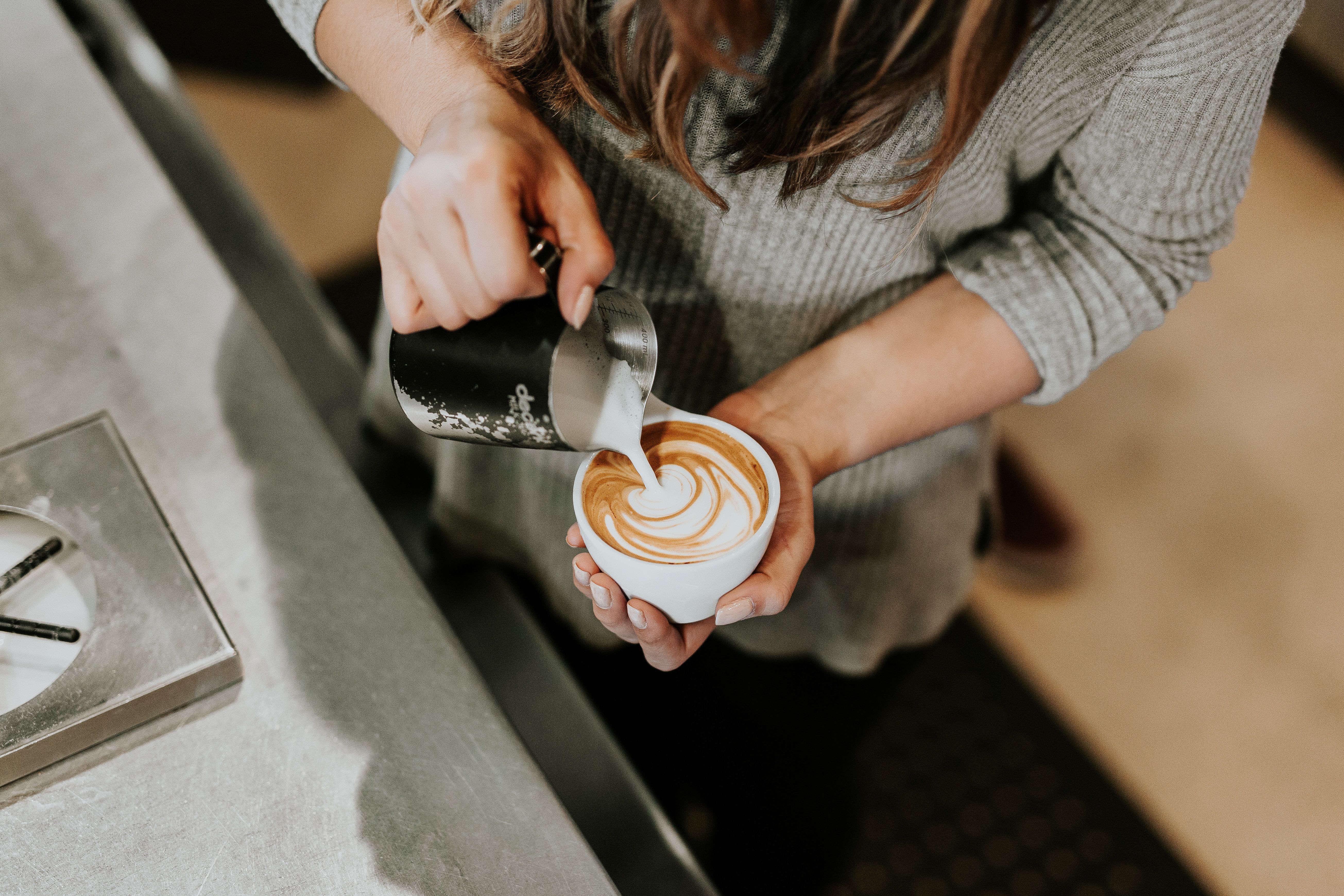 una ragazza al bar prepara un cappuccino coffee art