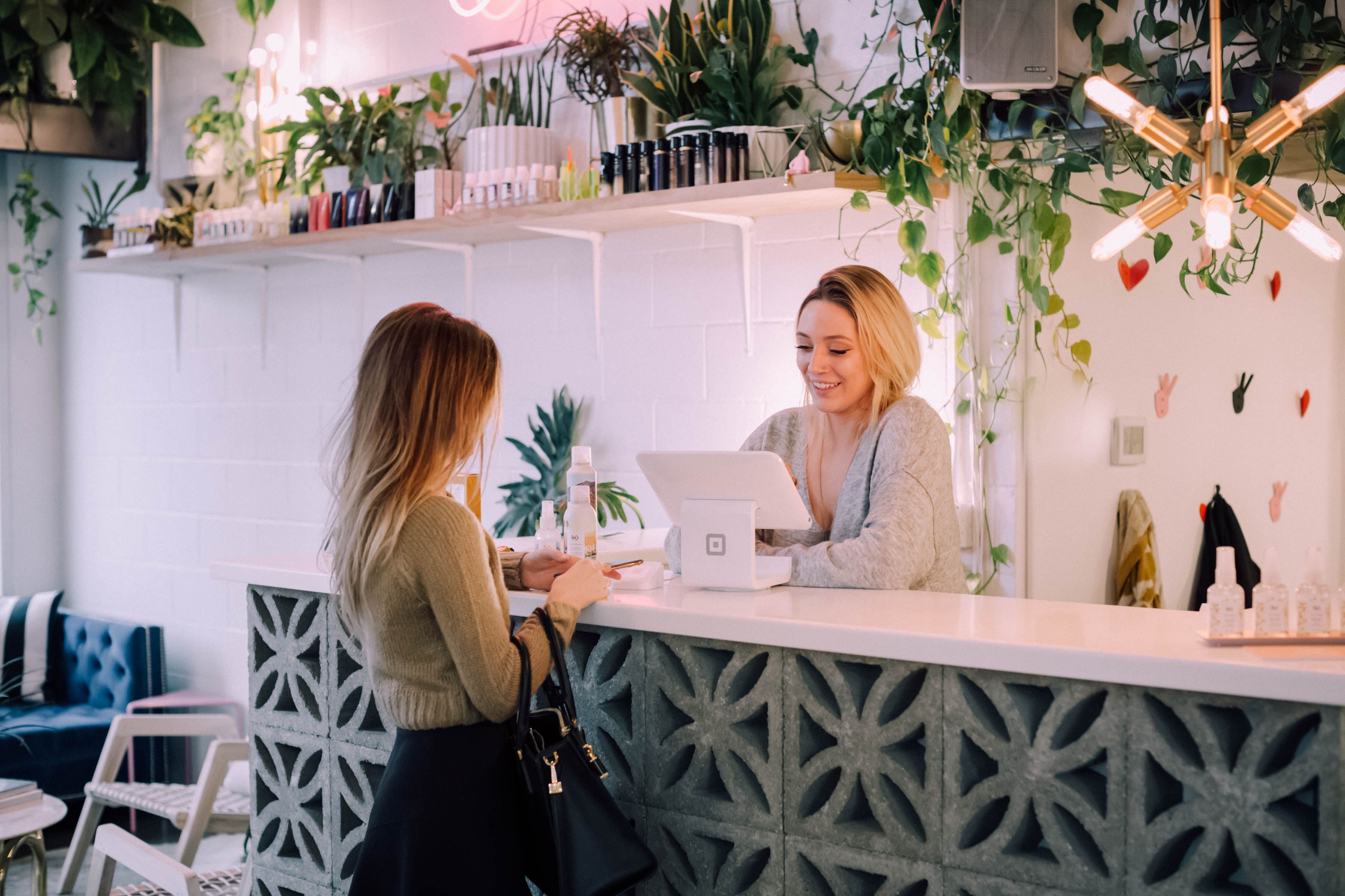 ragazza receptionist accoglie alla cassa cliente ristorante con pareti bianche