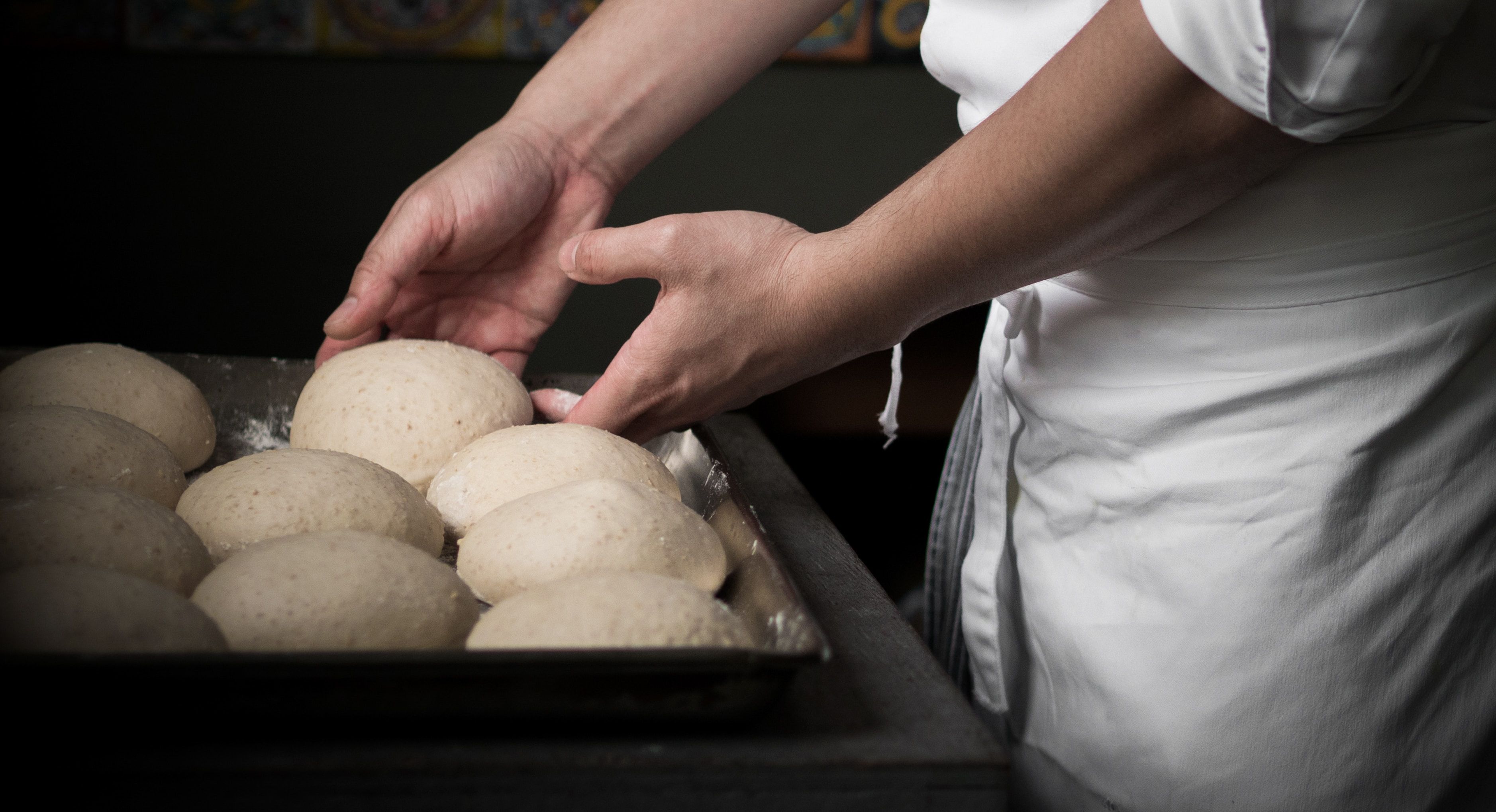 pizzaiolo maneggia i panetti di impasto per la pizza
