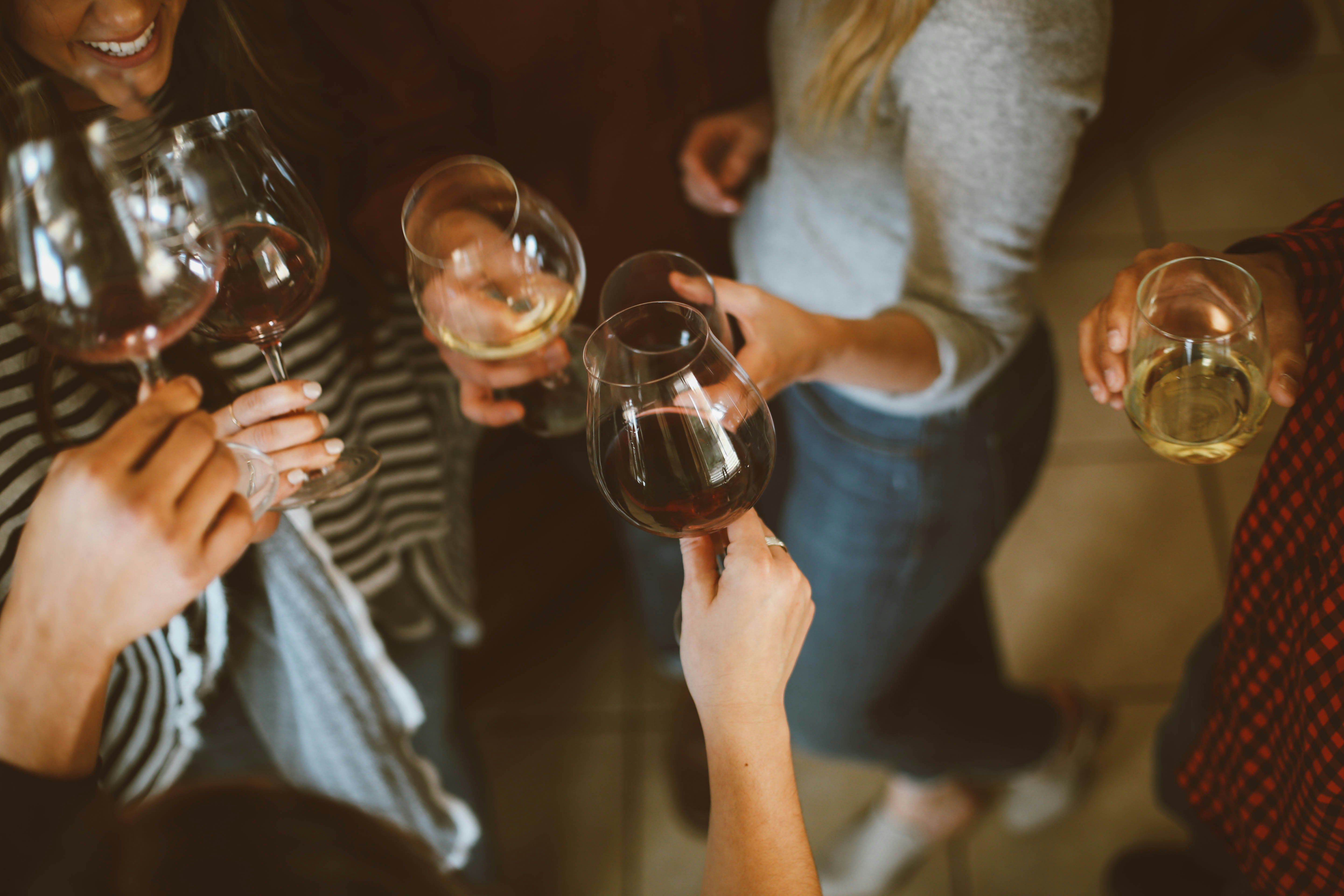 People holding glasses with white and red wine