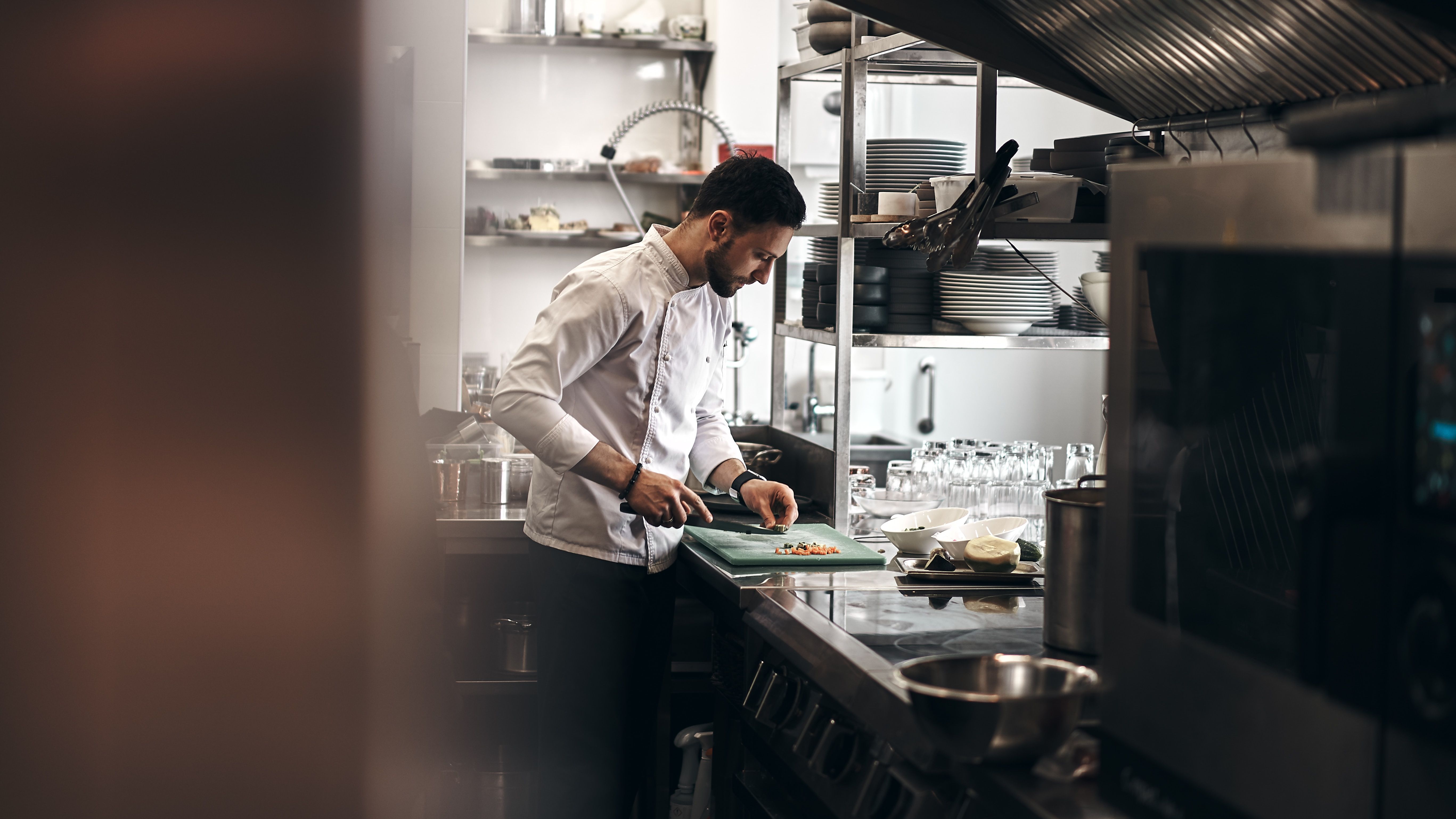 chef vestito di bianco finisce preparazione in cucina professionale ristorante