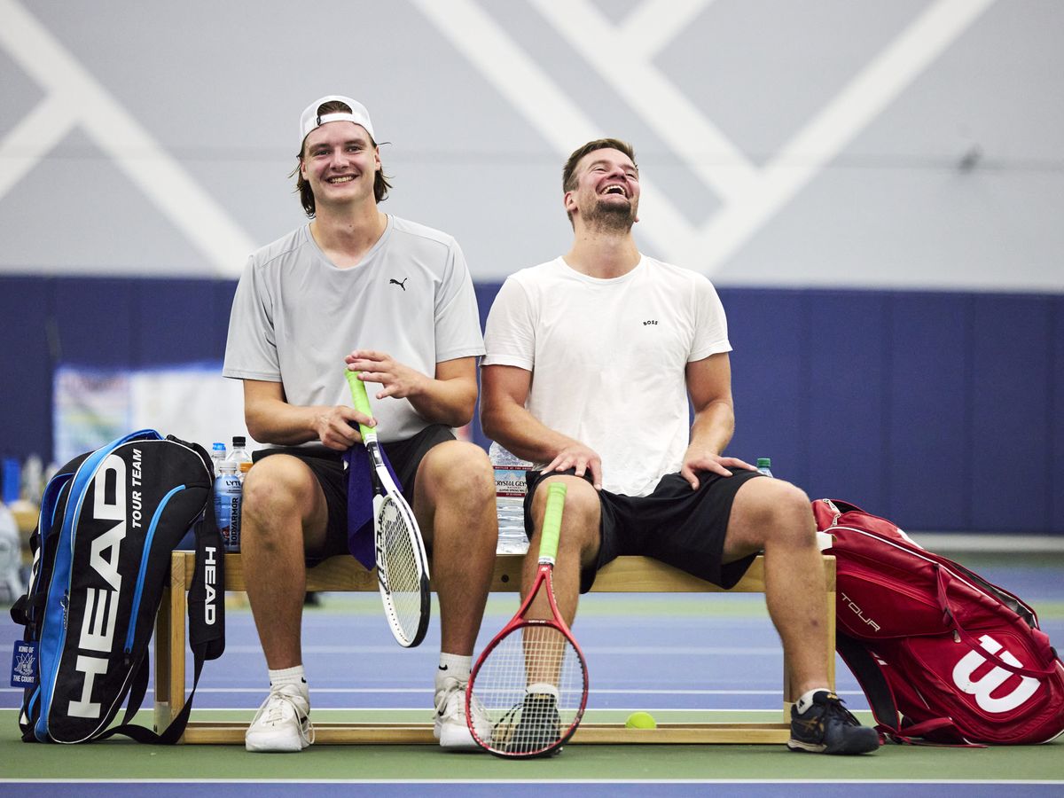 two happy men on a tennis bench after a match