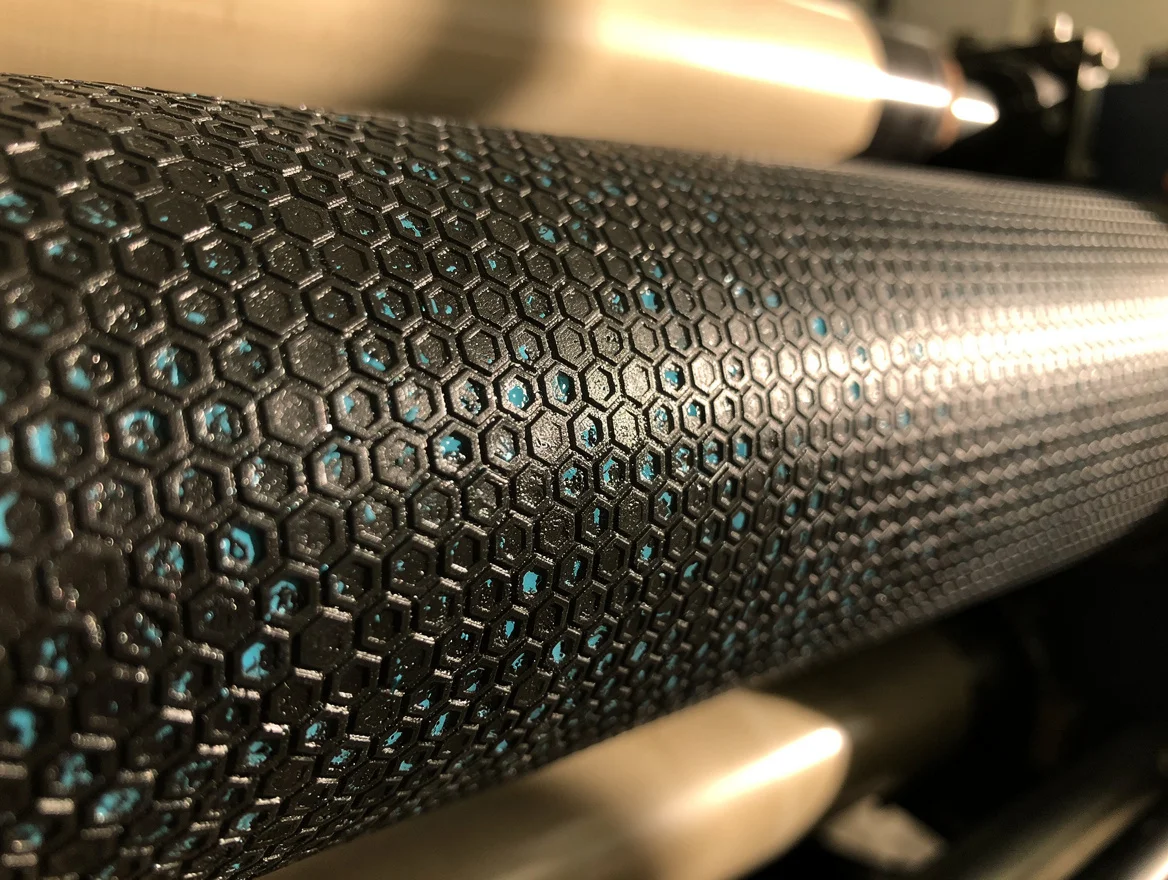 Macro view of a ceramic anilox roller showing laser-engraved cells with cyan ink