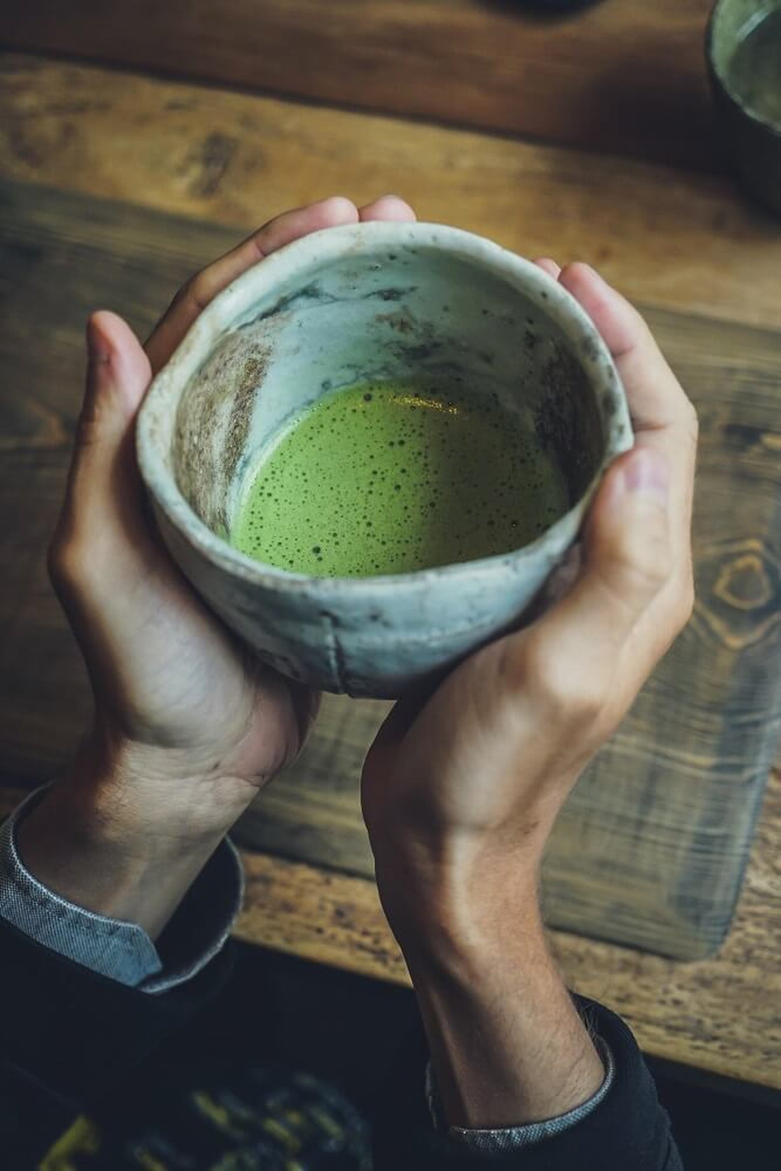 A cup of matcha latte with creamy foam on a cafe counter.